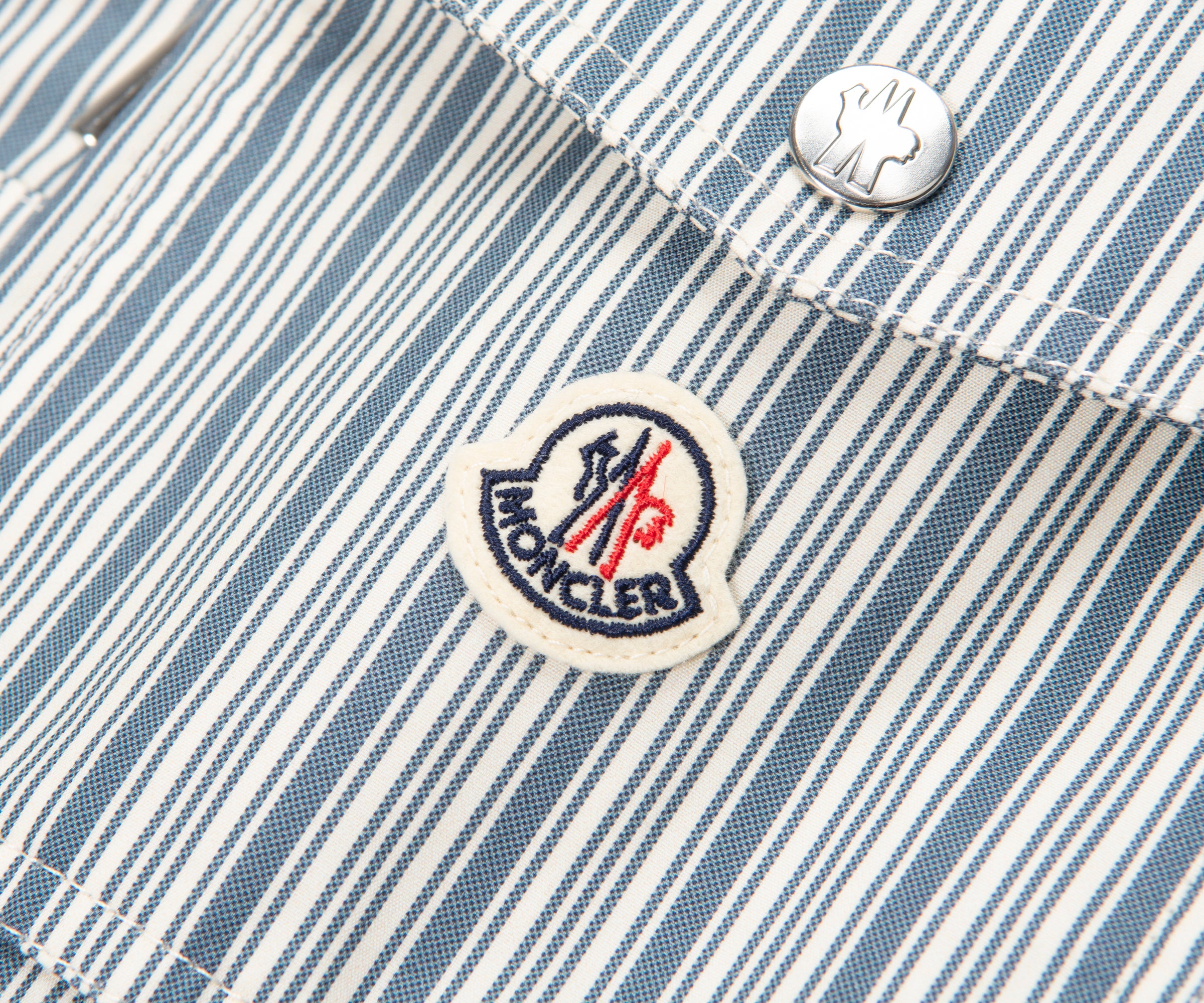 Close-up of a Moncler logo on a striped fabric background