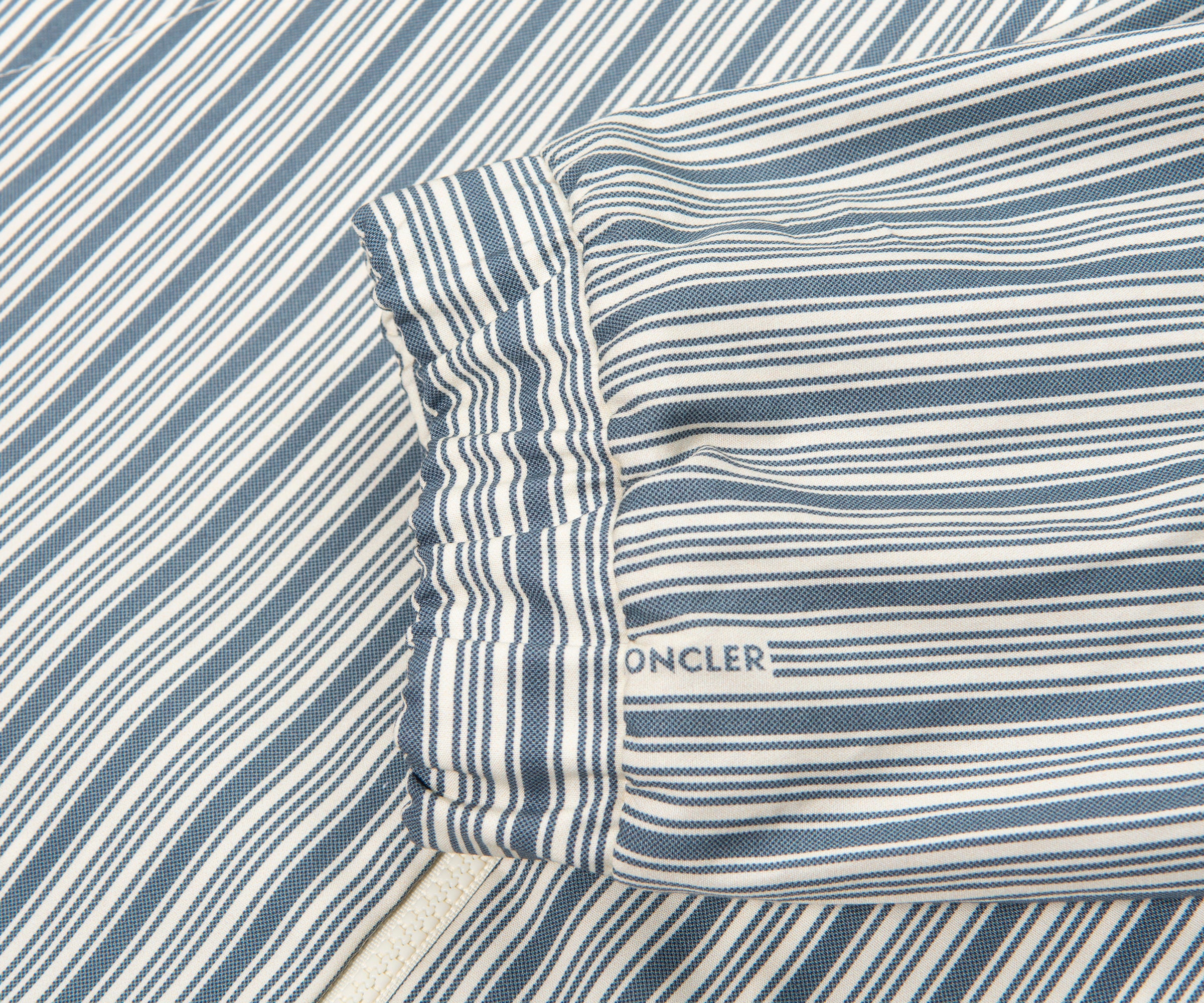 Close-up of a striped fabric with a visible brand logo, likely oncler.