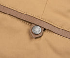 Close-up of a beige fabric with a brand label on a brown zipper.