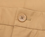 Close-up of a beige fabric with a button and zipper, featuring the Moncler brand logo.