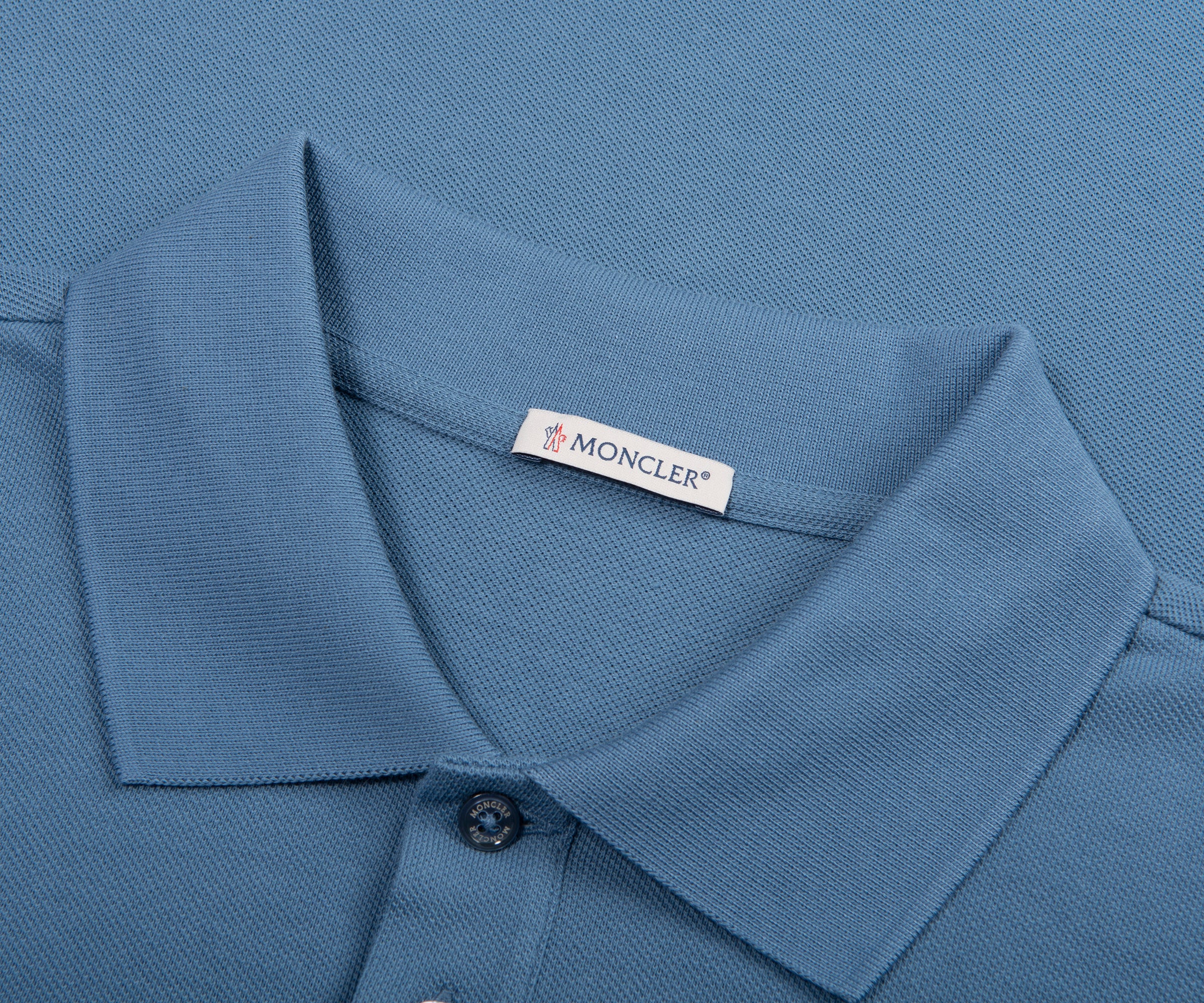 Close-up of a blue polo shirt with a Moncler label.