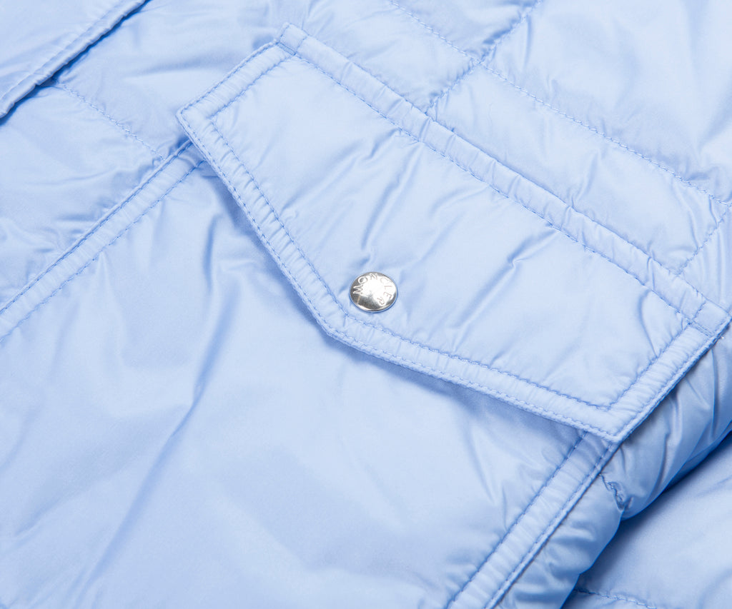 Close-up of a light blue quilted jacket with a button.