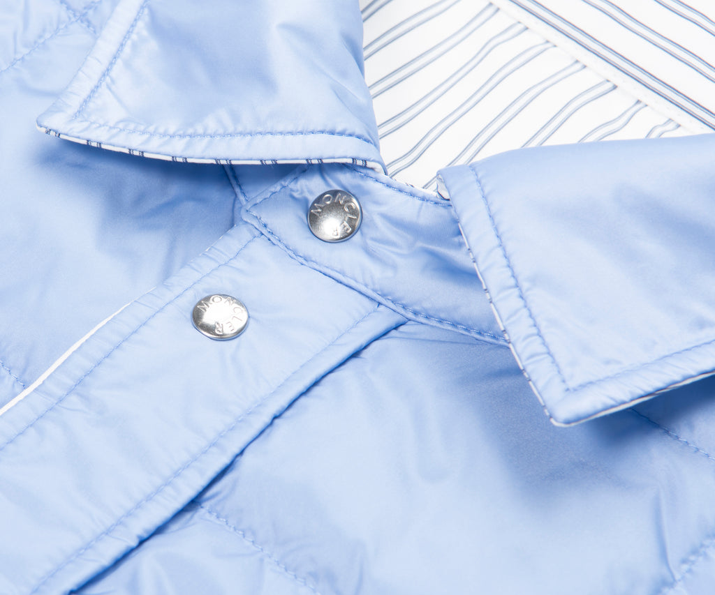 Close-up of a light blue denim jacket with buttons on a white background
