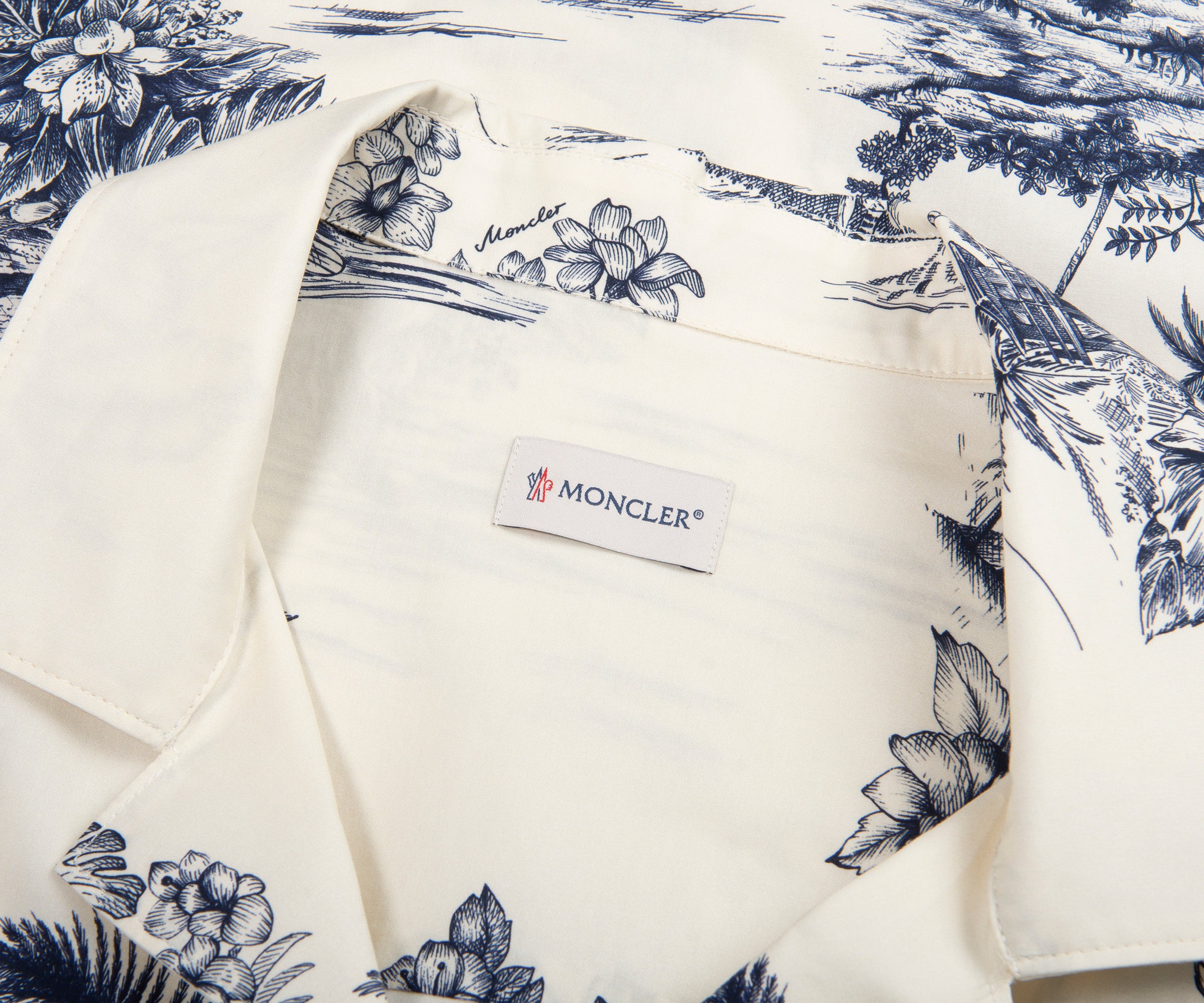 White garment with blue floral pattern and Moncler label on a matching fabric background