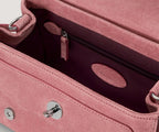 Close-up of a pink handbag with a zipper and metallic accents.