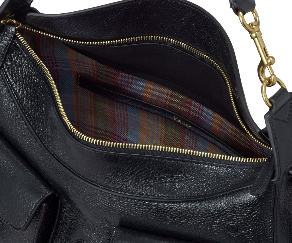 Black leather handbag with gold zipper and plaid lining on a white background