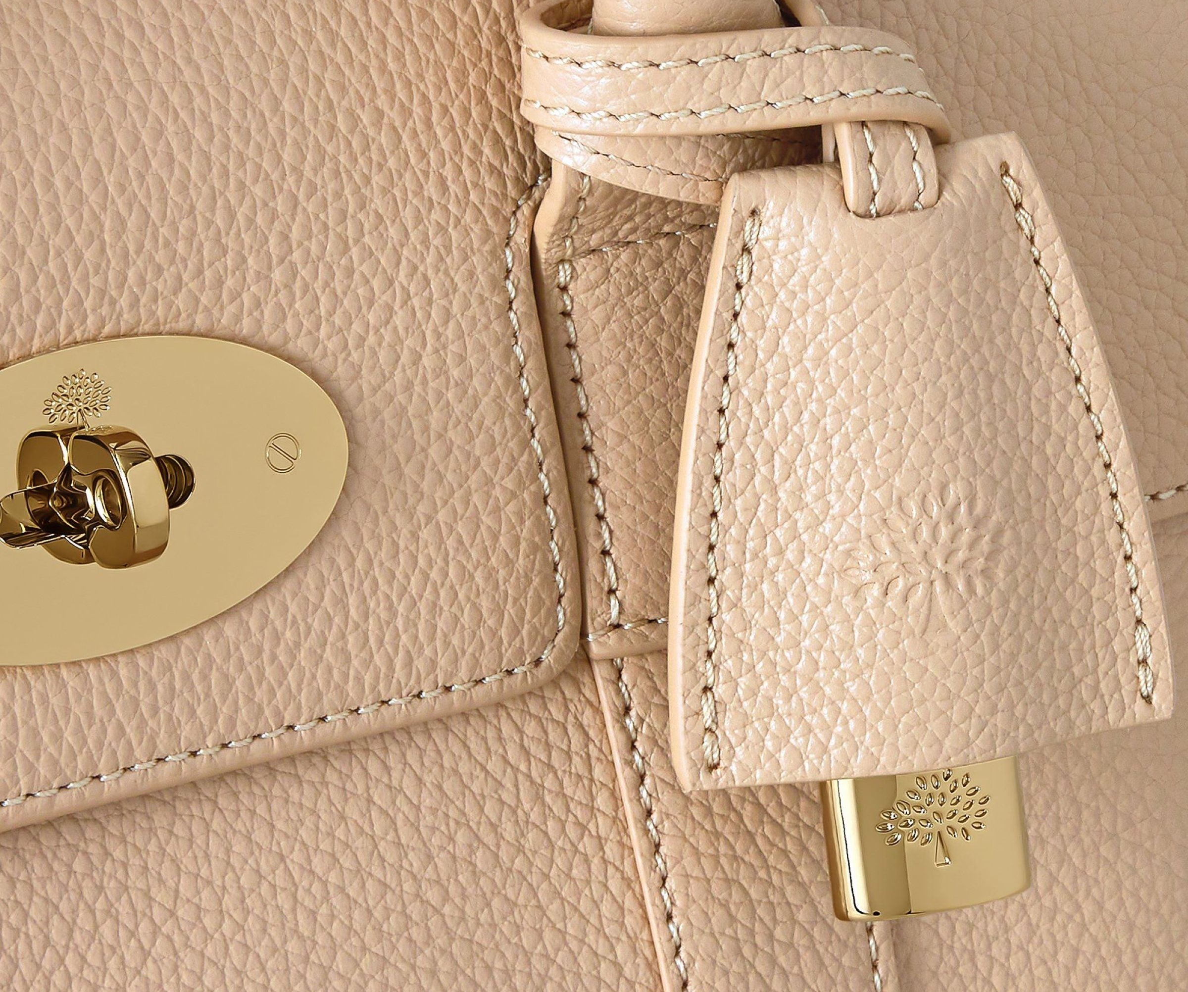 Close-up of a beige leather handbag with gold hardware