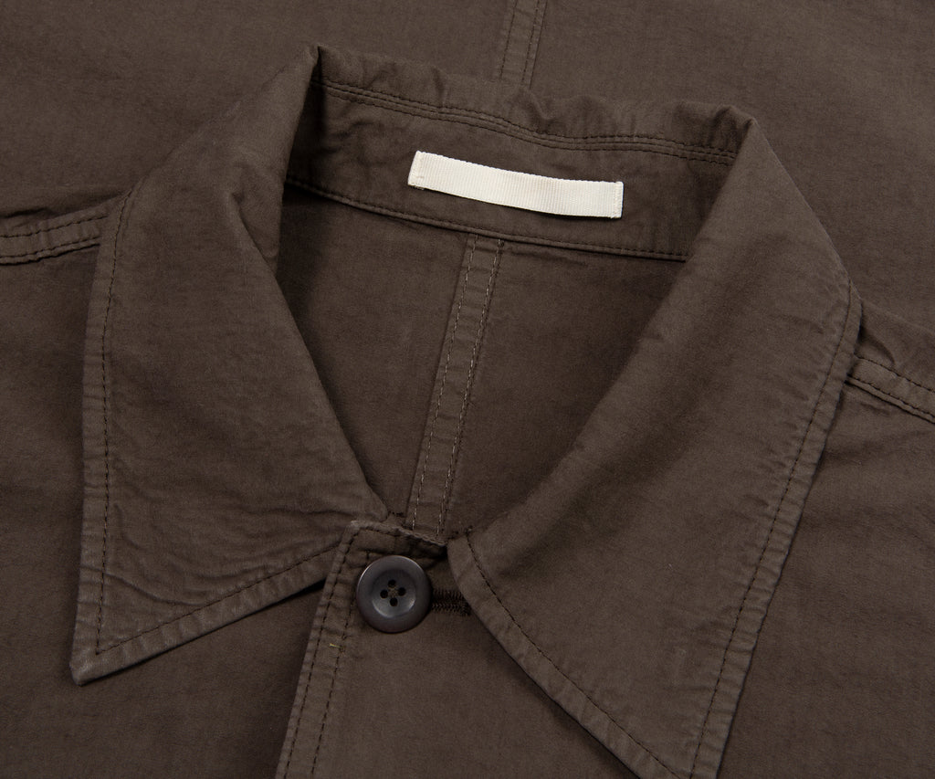 Close-up of a brown jacket collar with a button and label.