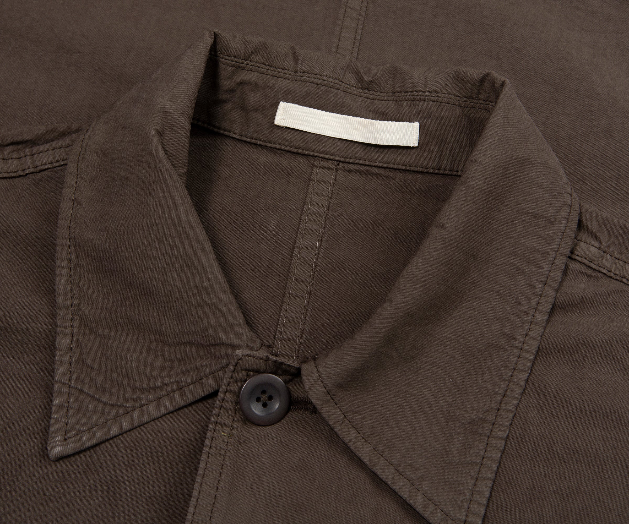 Close-up of a brown jacket collar with a button and label.