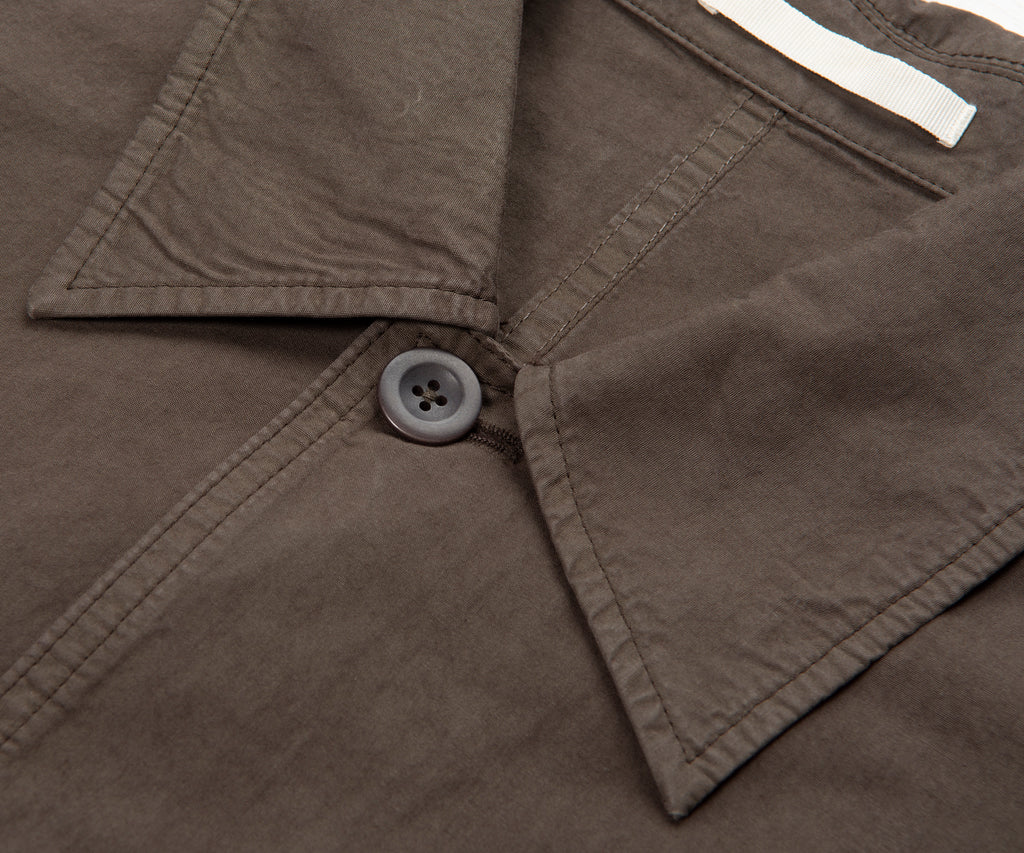Close-up of a brown jacket collar with a button and white label.