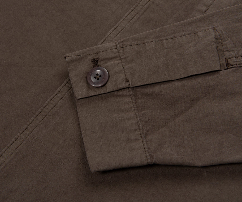 Close-up of a button on a brown fabric, likely a shirt or jacket.