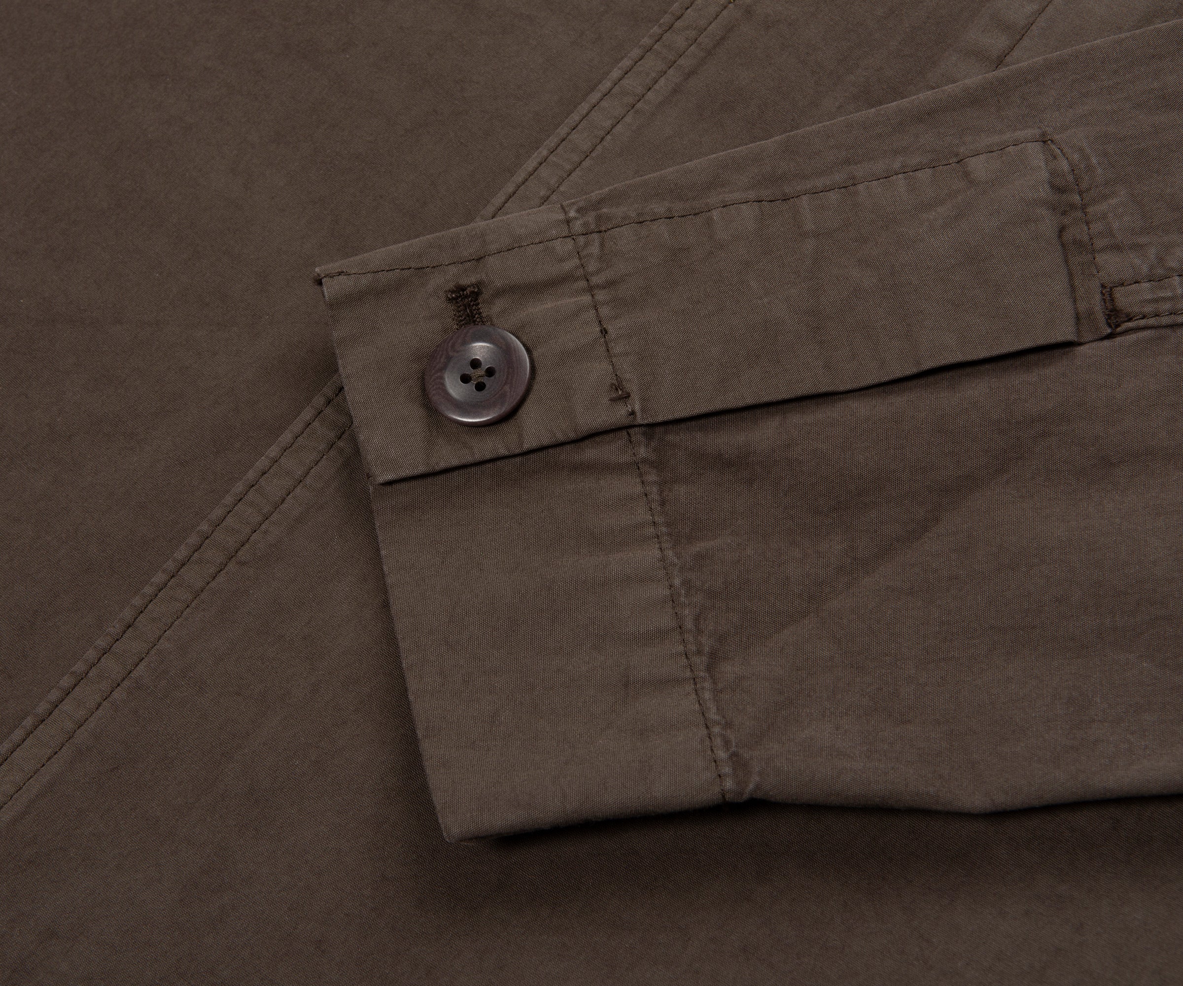 Close-up of a button on a brown fabric, likely a shirt or jacket.