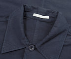 Close-up of a navy blue shirt collar with a button and a brand label.