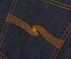 Close-up of dark denim fabric with orange stitching forming a pattern.