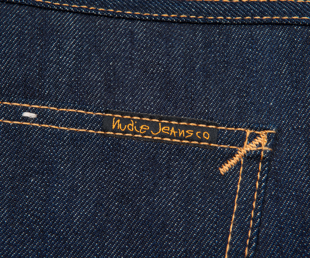 Close-up of a blue denim fabric with 'Nude Jeans Co.' branding.