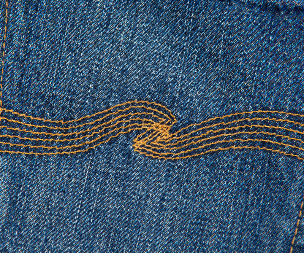 Close-up of blue denim fabric with yellow stitching