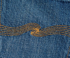Close-up of blue denim fabric with yellow stitching