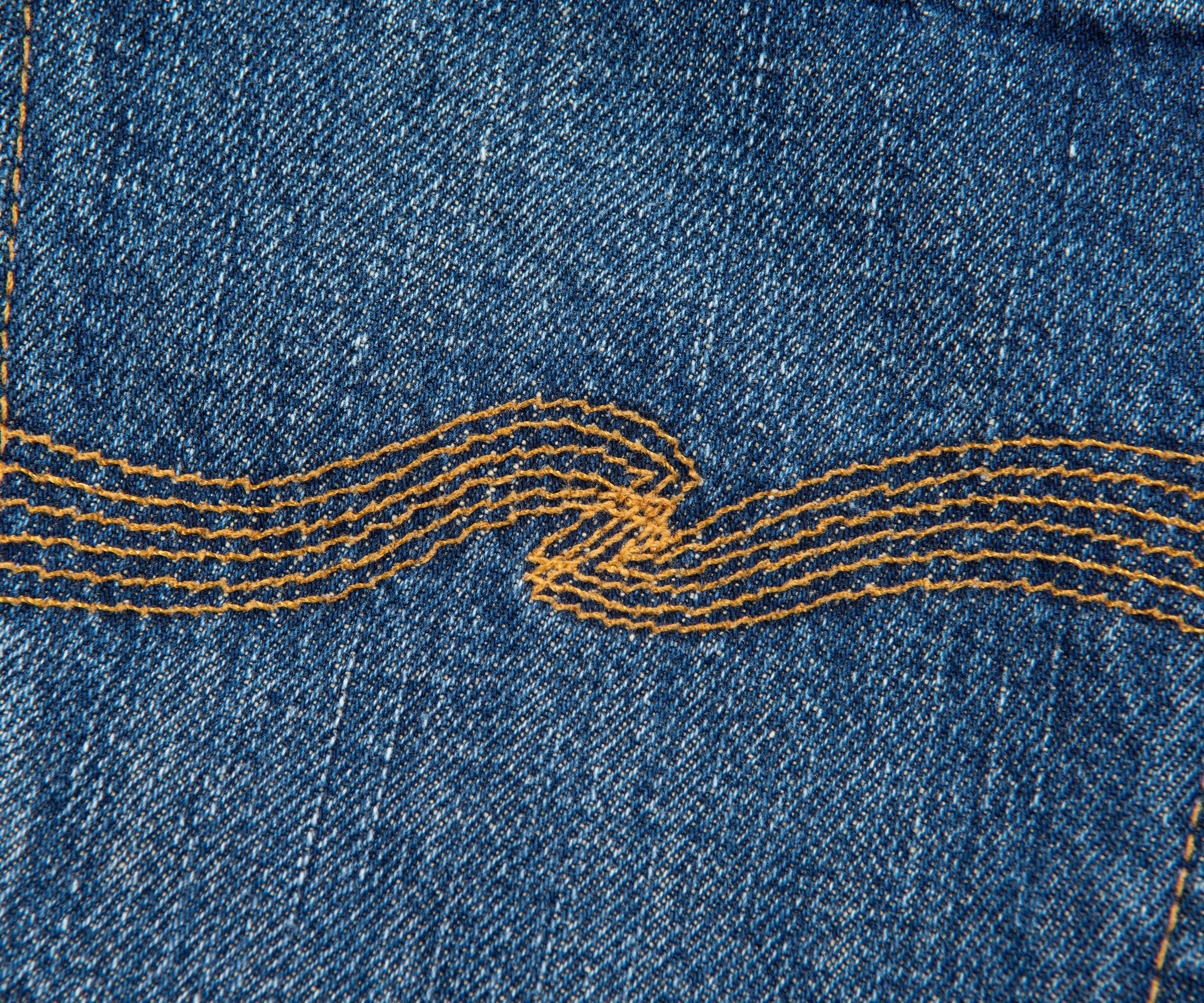 Close-up of blue denim fabric with yellow stitching