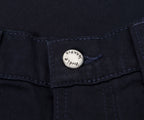 Close-up of a button on a dark fabric, likely jeans, with 'Nudie Jeans' branding.
