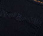 Close-up of a black fabric with embroidered design and 'Nudie Jeans' branding.