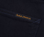 Nudie Jeans logo on a dark fabric background