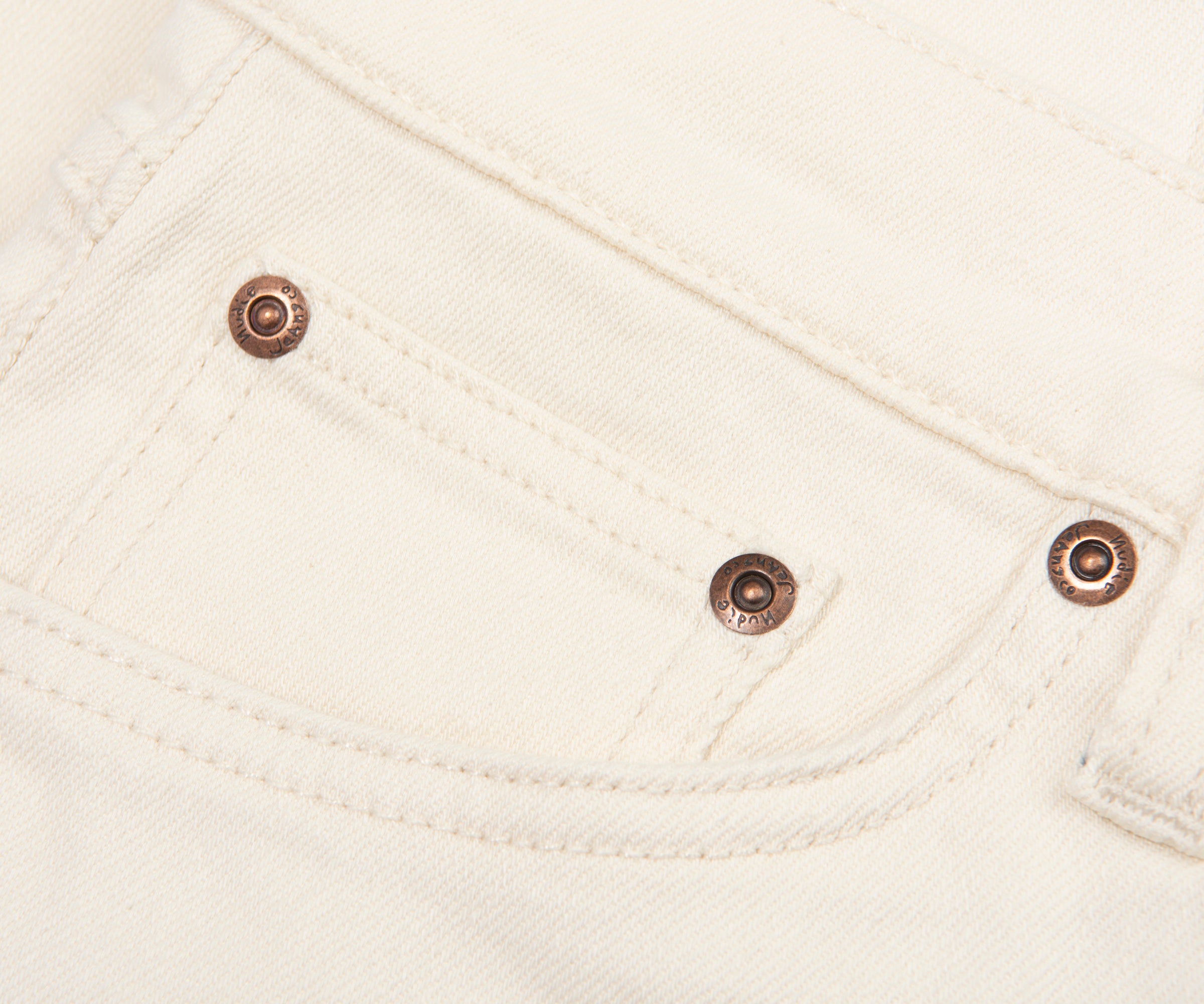 Close-up of a white fabric pocket with metal buttons.