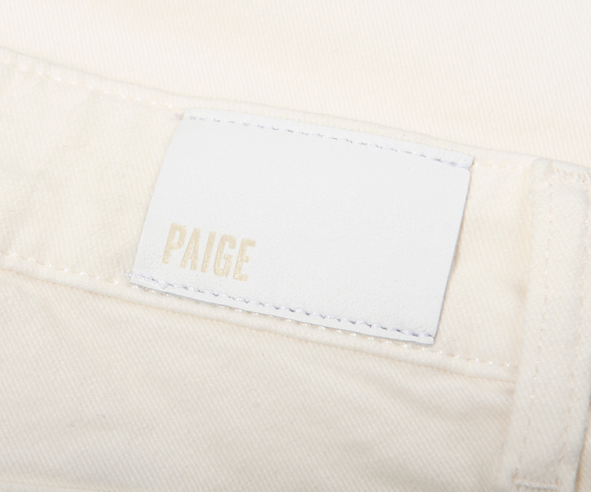 Close-up of a 'Paige' label on beige fabric