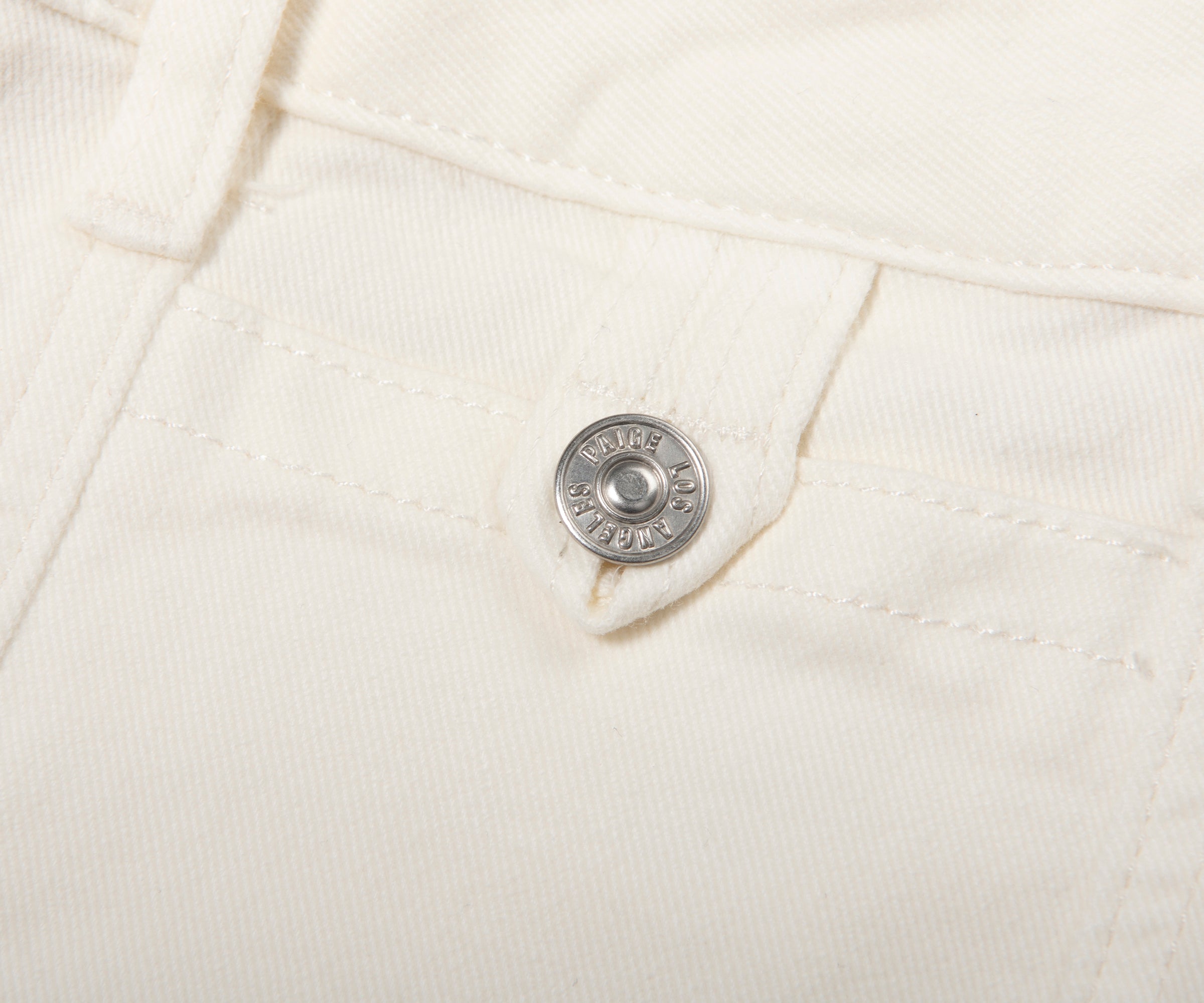 Close-up of a button on a white denim jacket with 'Levi's' branding.
