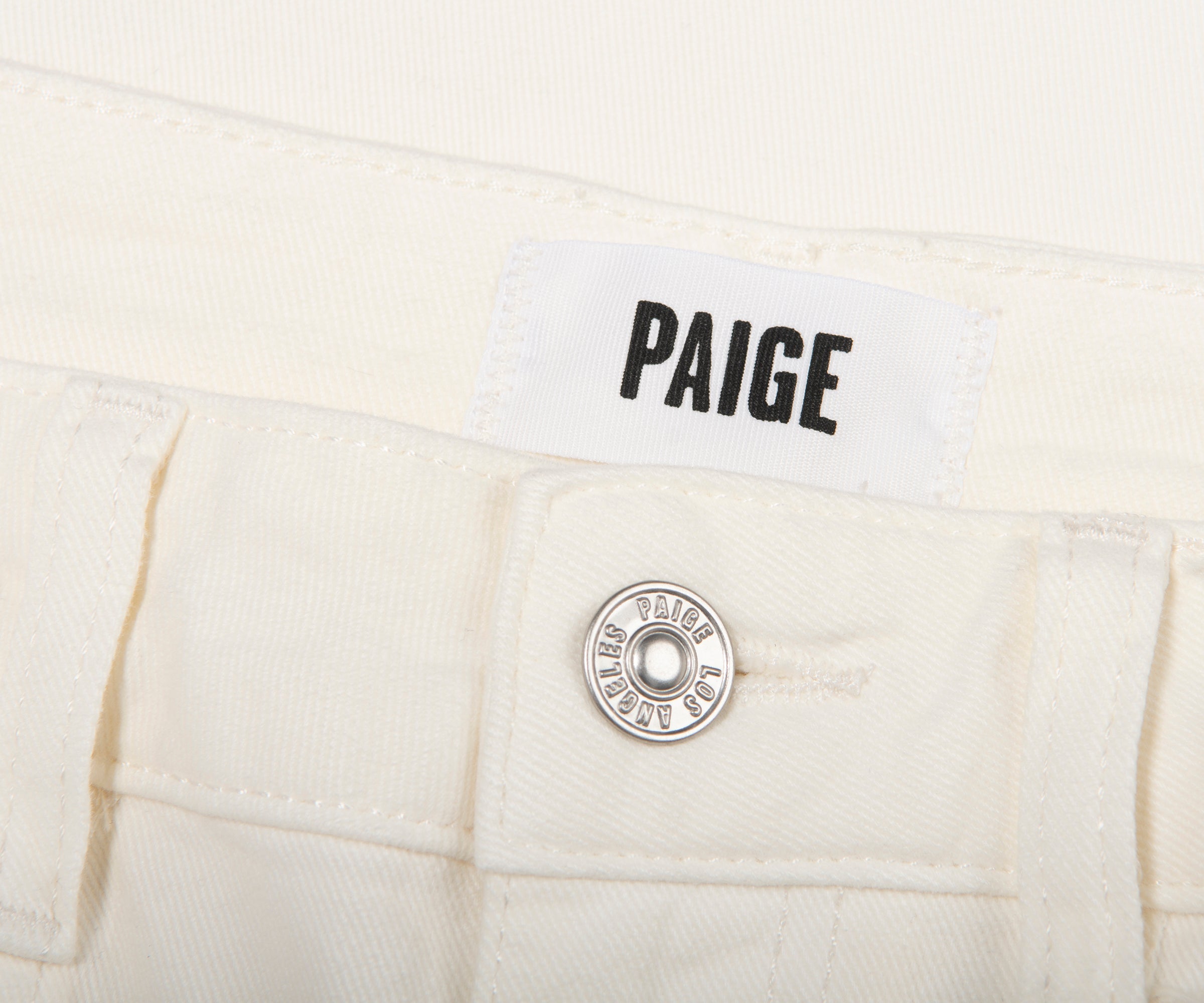 Close-up of a white denim pocket with 'PAIGE' branding.