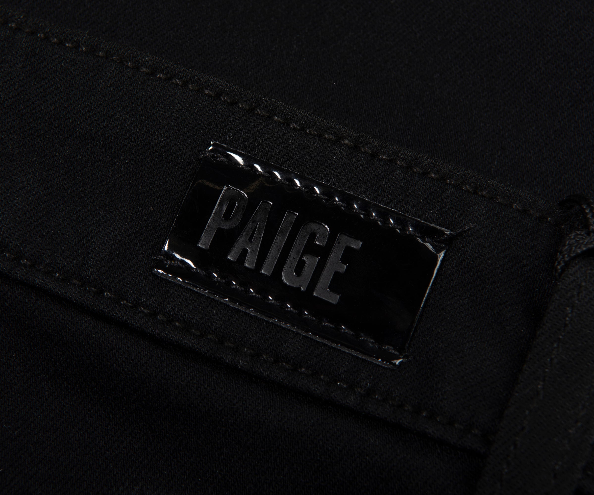 Close-up of a black bag with 'PAIGE' branding on a dark background