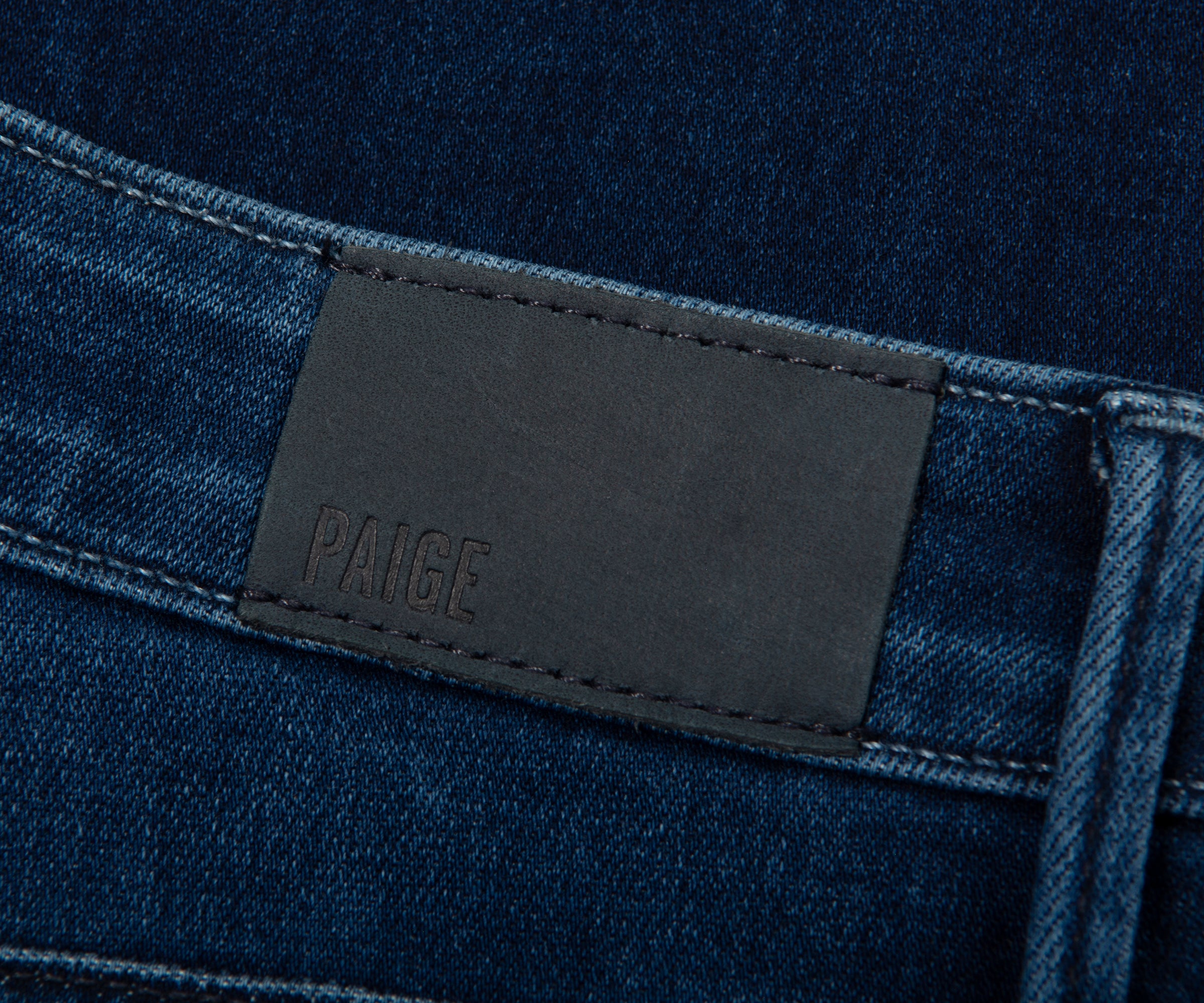Close-up of blue jeans with a black label on a dark background