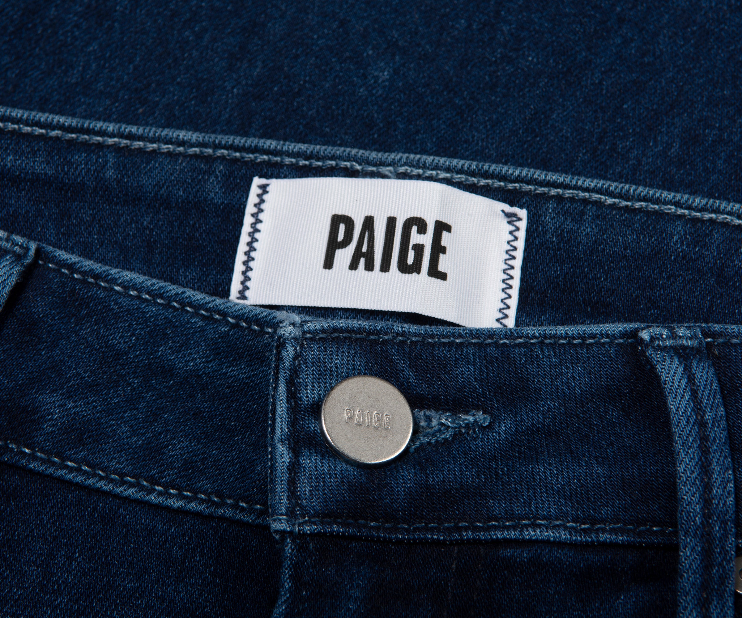 Close-up of a blue denim garment with a Paige label.