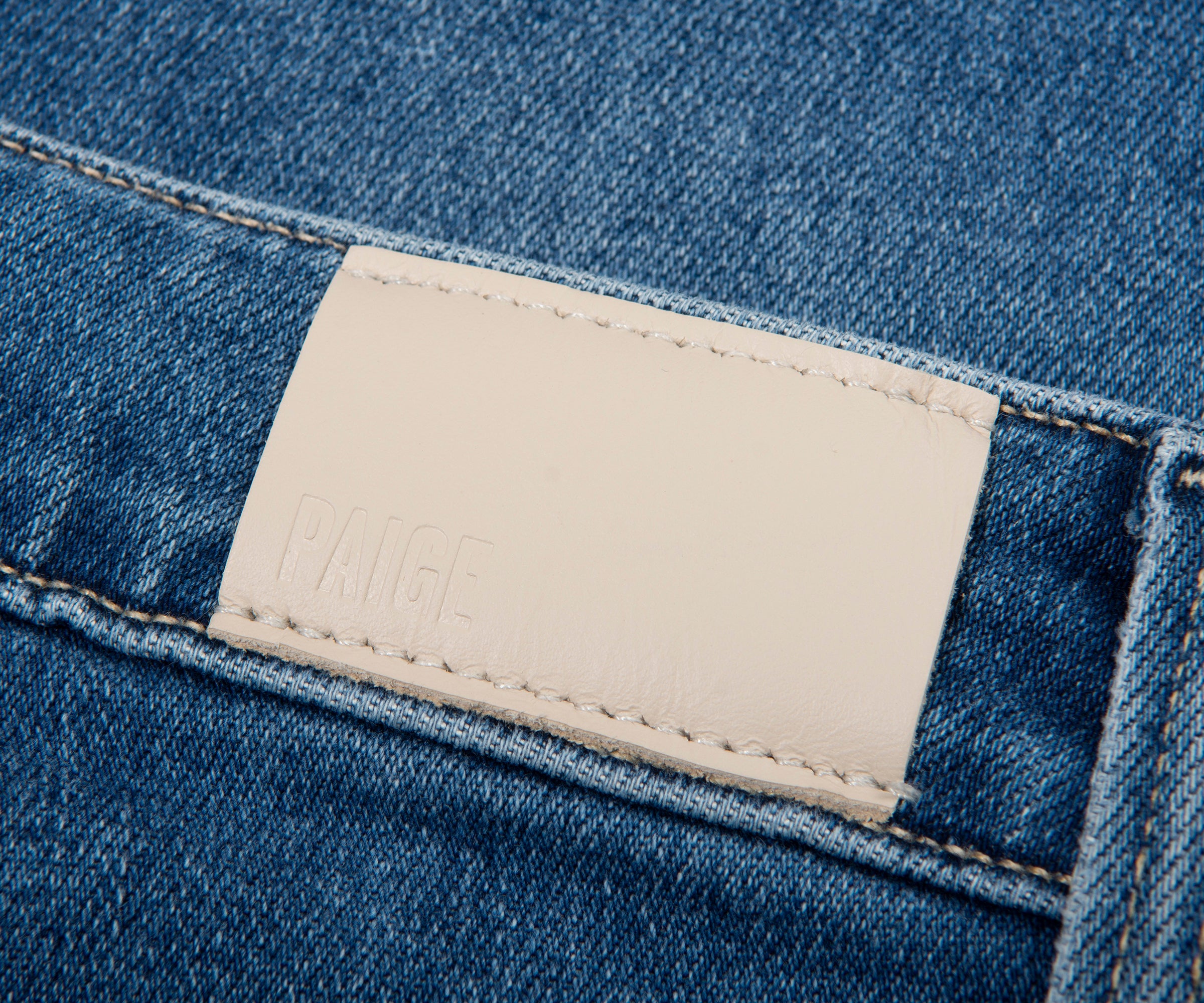 Close-up of a blue denim fabric with a beige label featuring the brand name 'Kaner'.