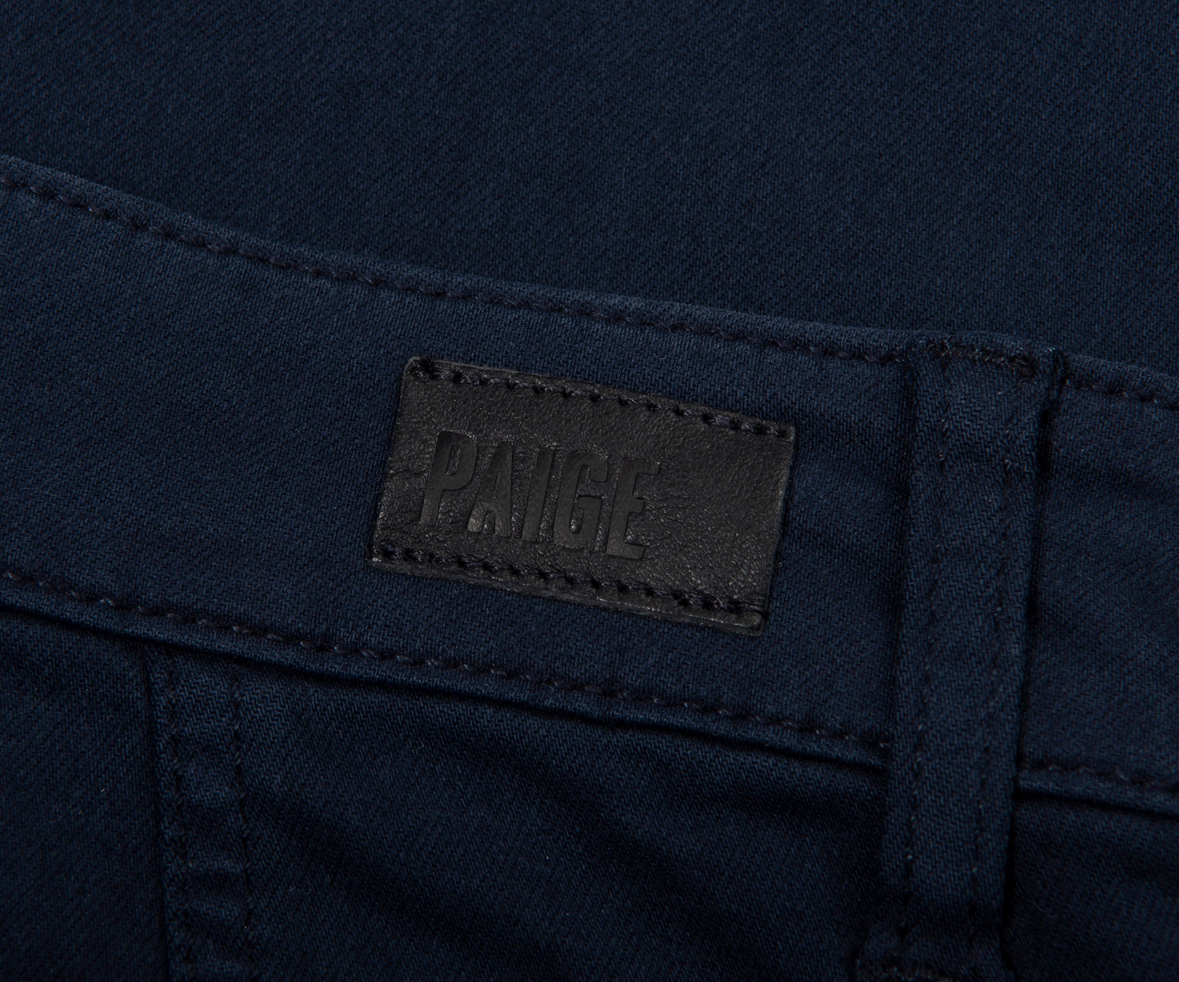 Close-up of a navy blue fabric with a brand label on a dark background
