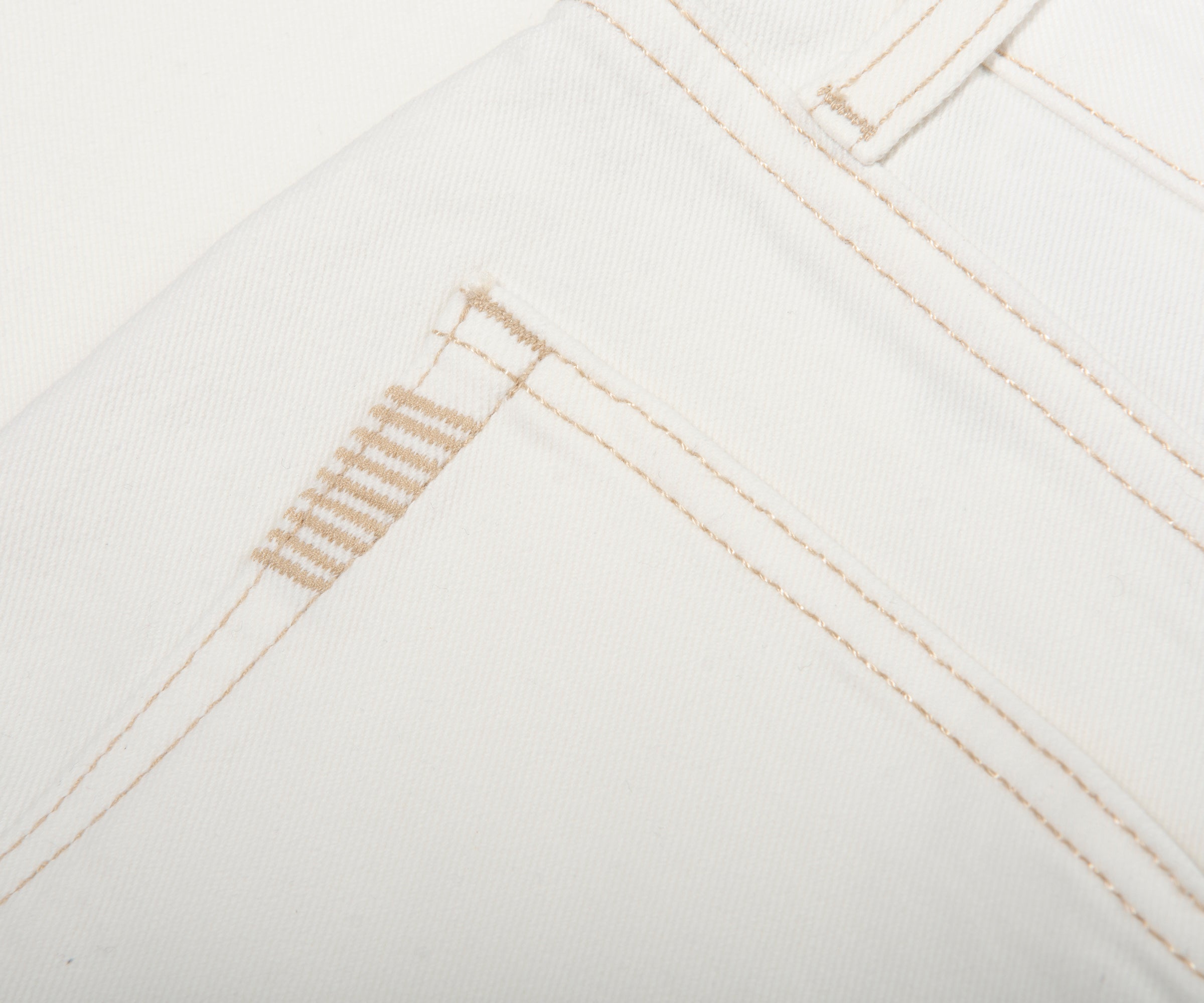 Close-up of white fabric with beige stitching on a white background