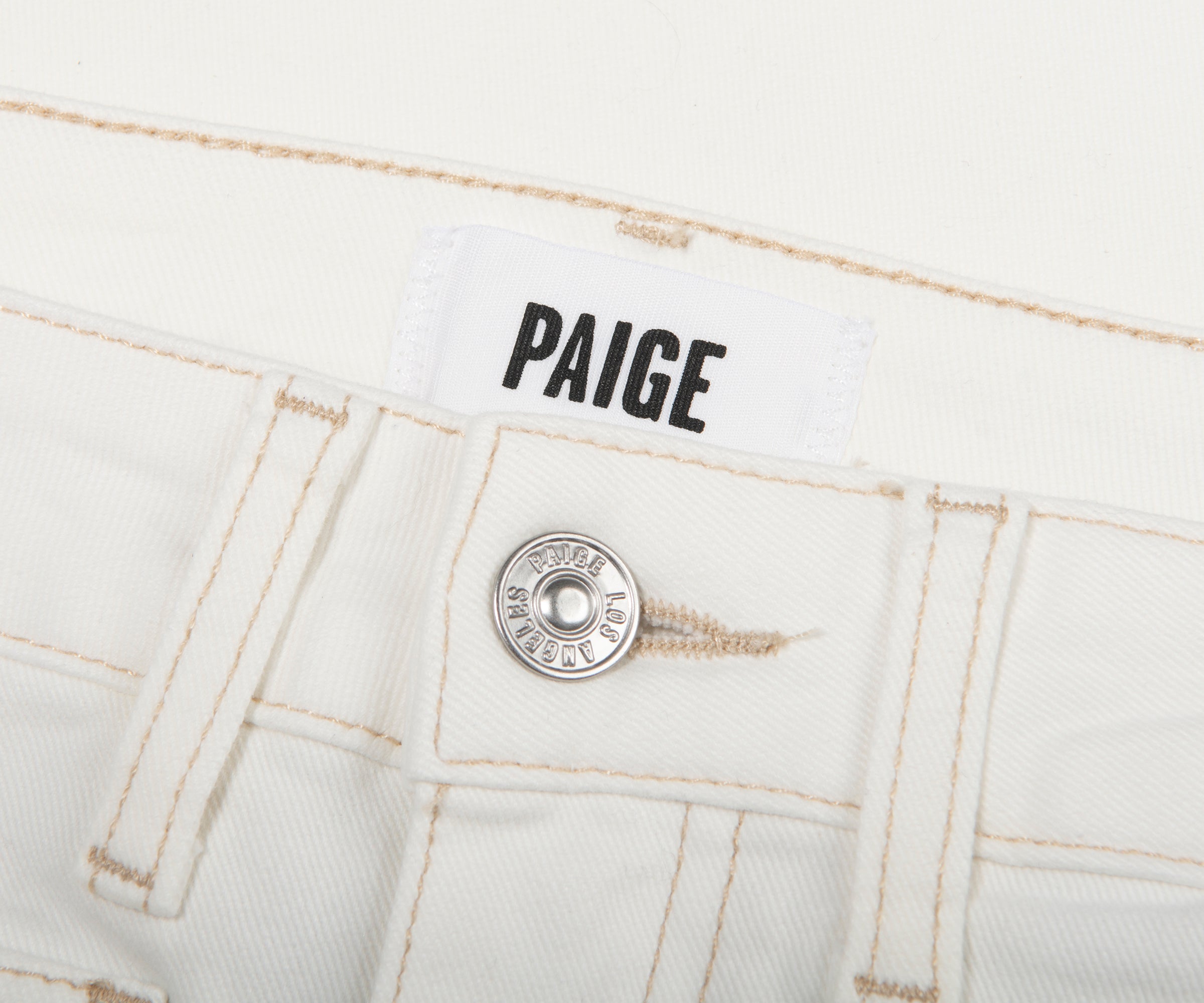 Close-up of white jeans with 'Paige' branding on a white background