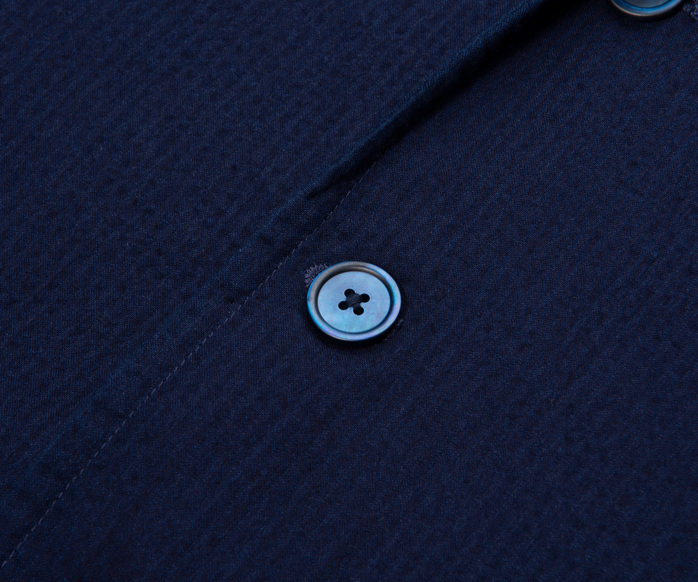 Close-up of a button on a navy blue textured shirt