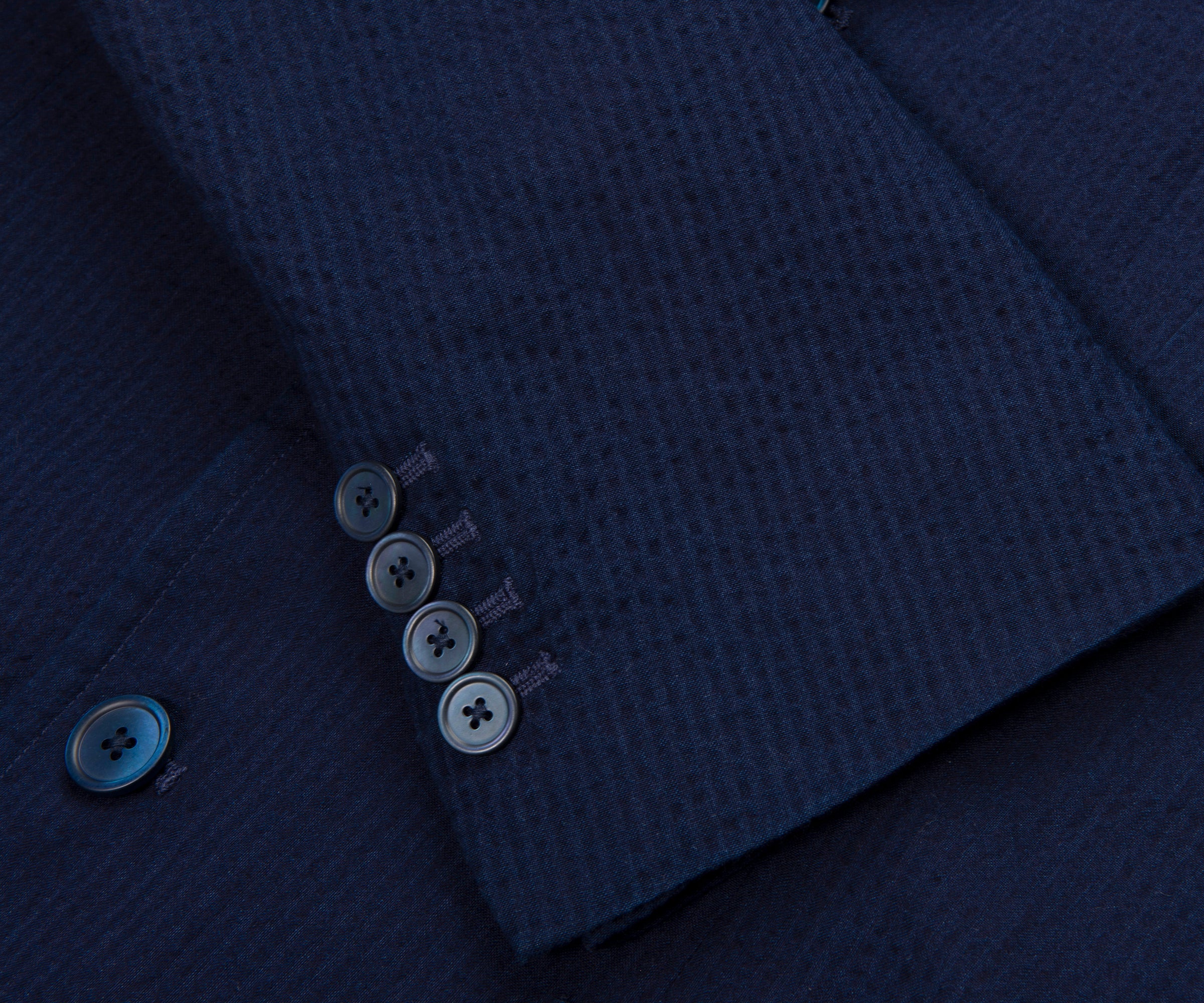 Close-up of a dark blue textured fabric with buttons on a matching garment.