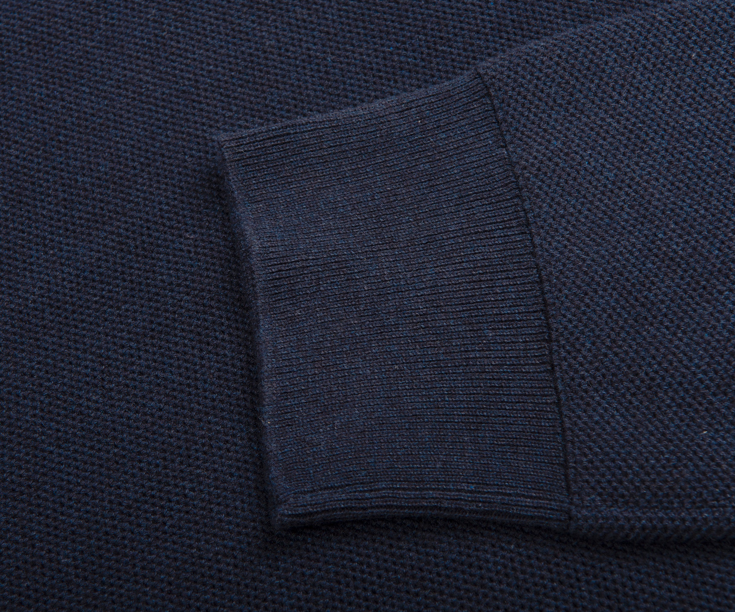 Close-up of a dark blue textured fabric with a folded edge.