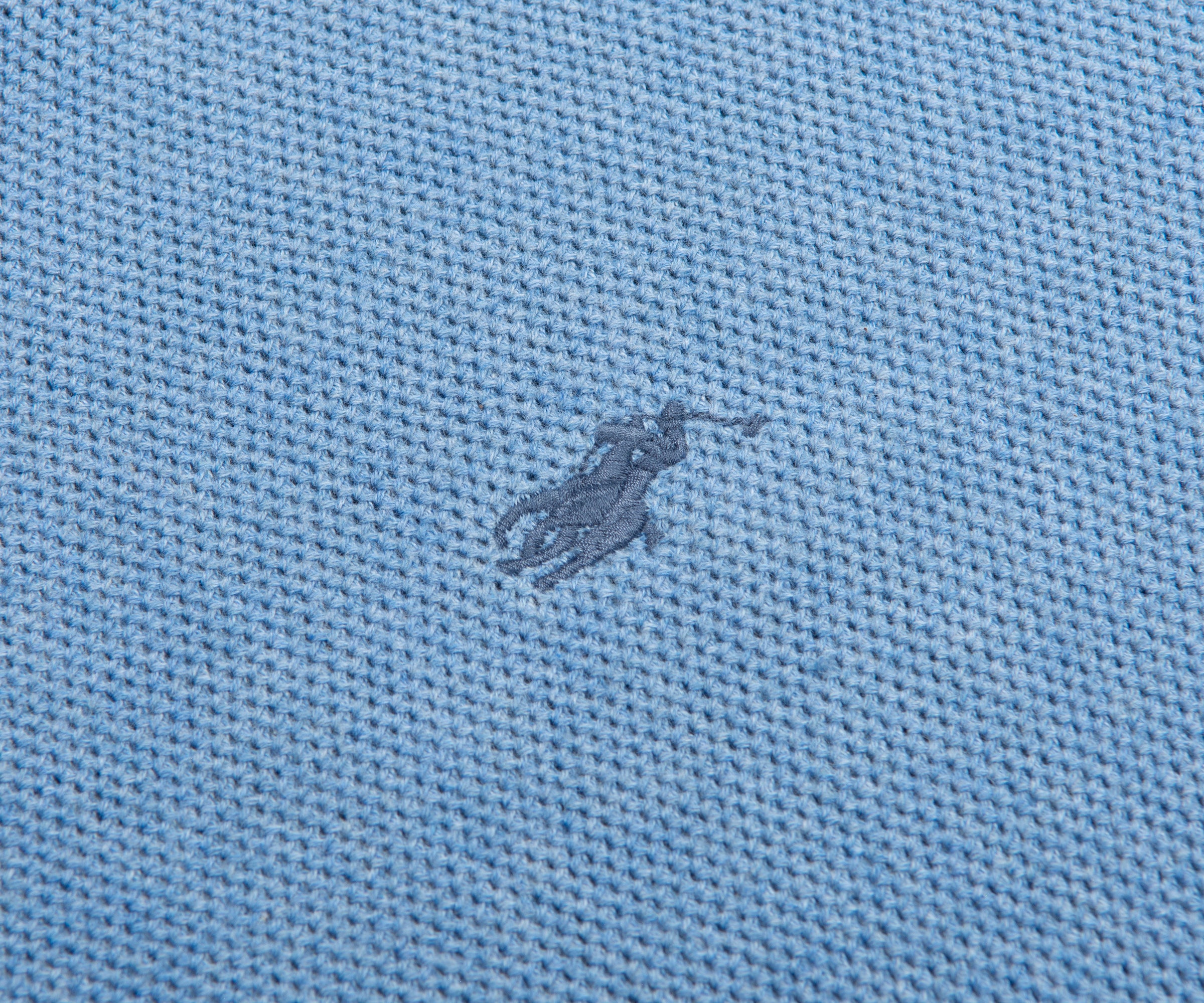 Close-up of a textured blue fabric with a small logo or emblem.