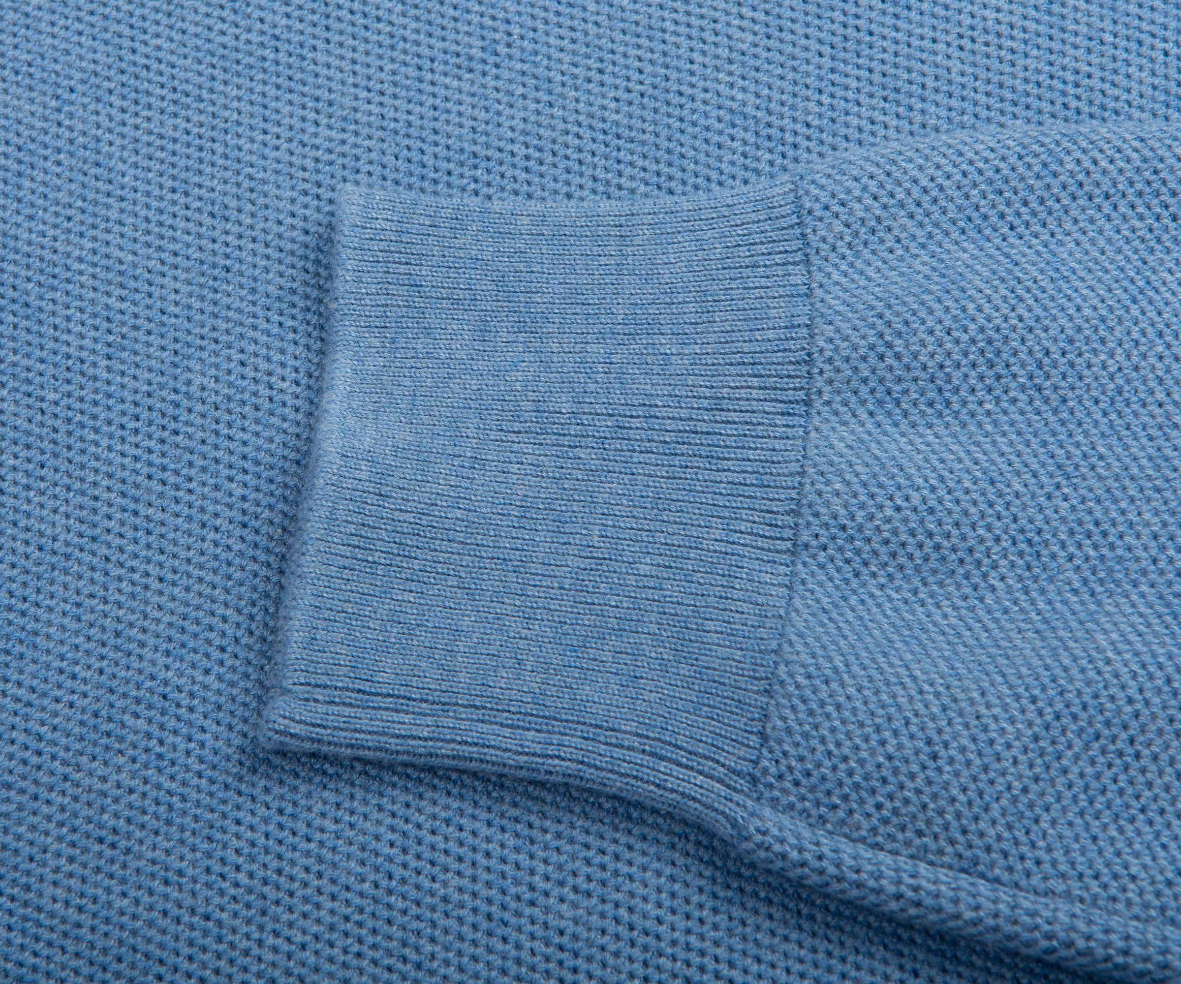 Close-up of a blue textured fabric with a pocket detail