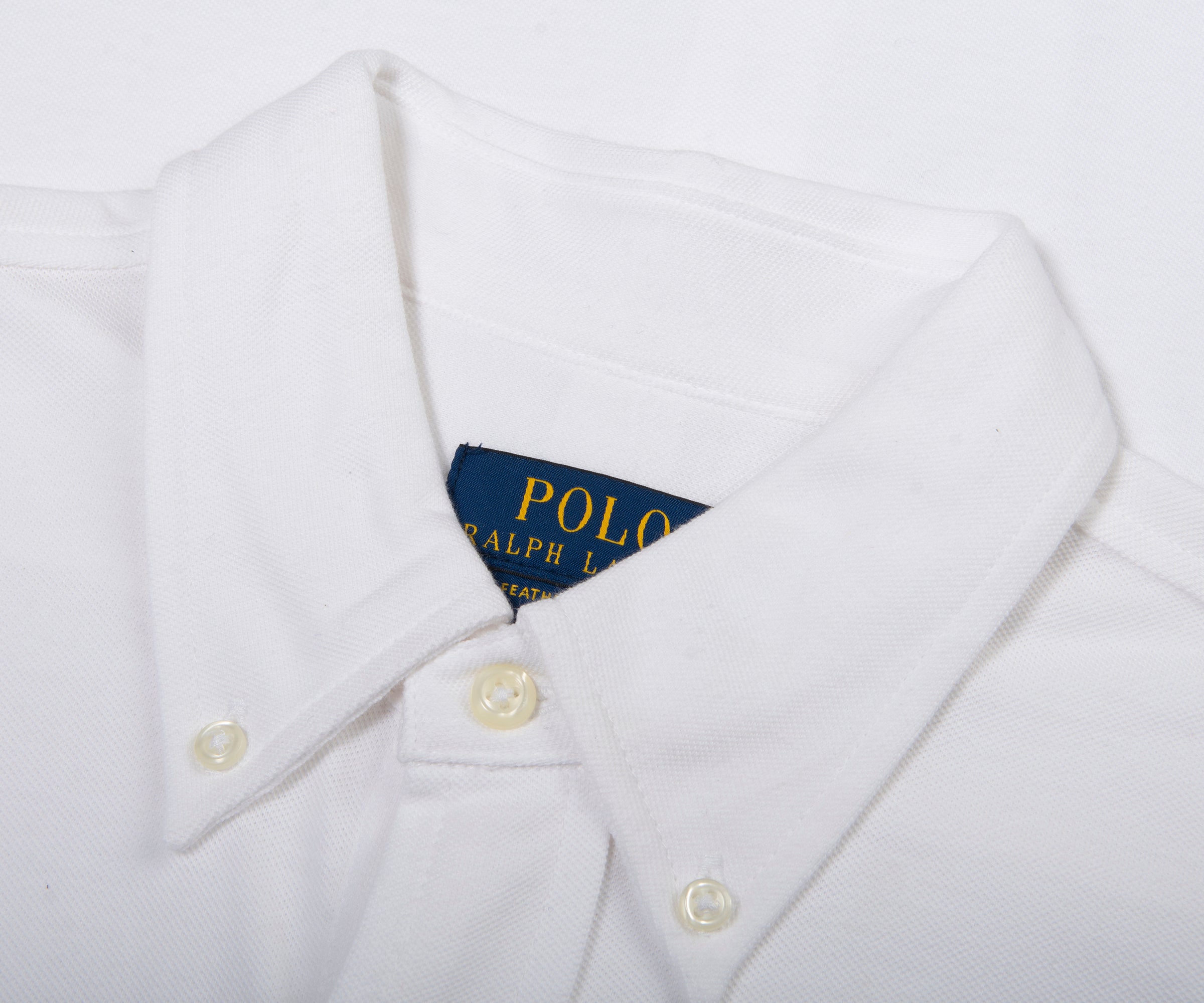 Close-up of a white shirt with a Polo Ralph Lauren label on a white background