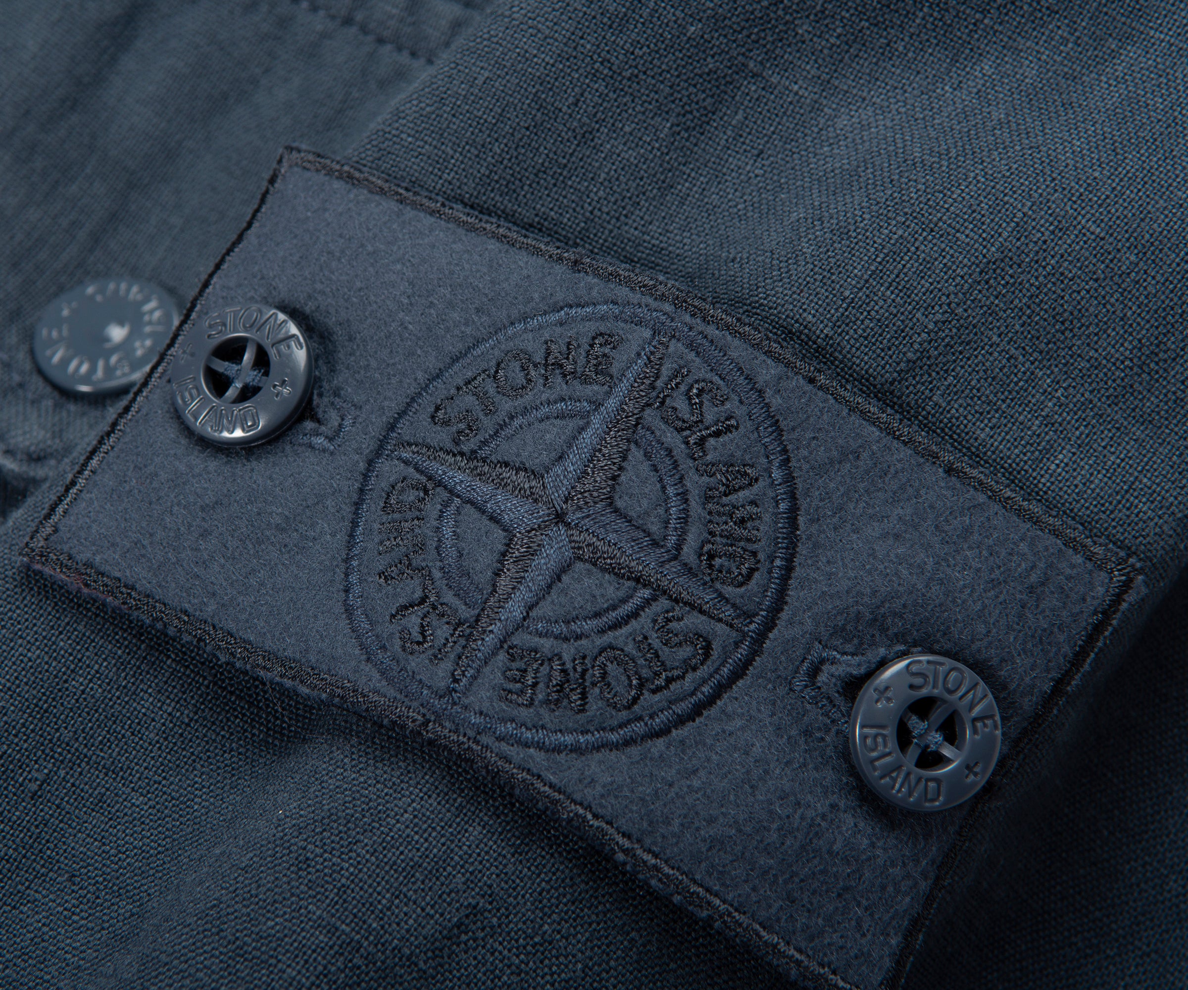Close-up of a Stone Island logo on a dark fabric background
