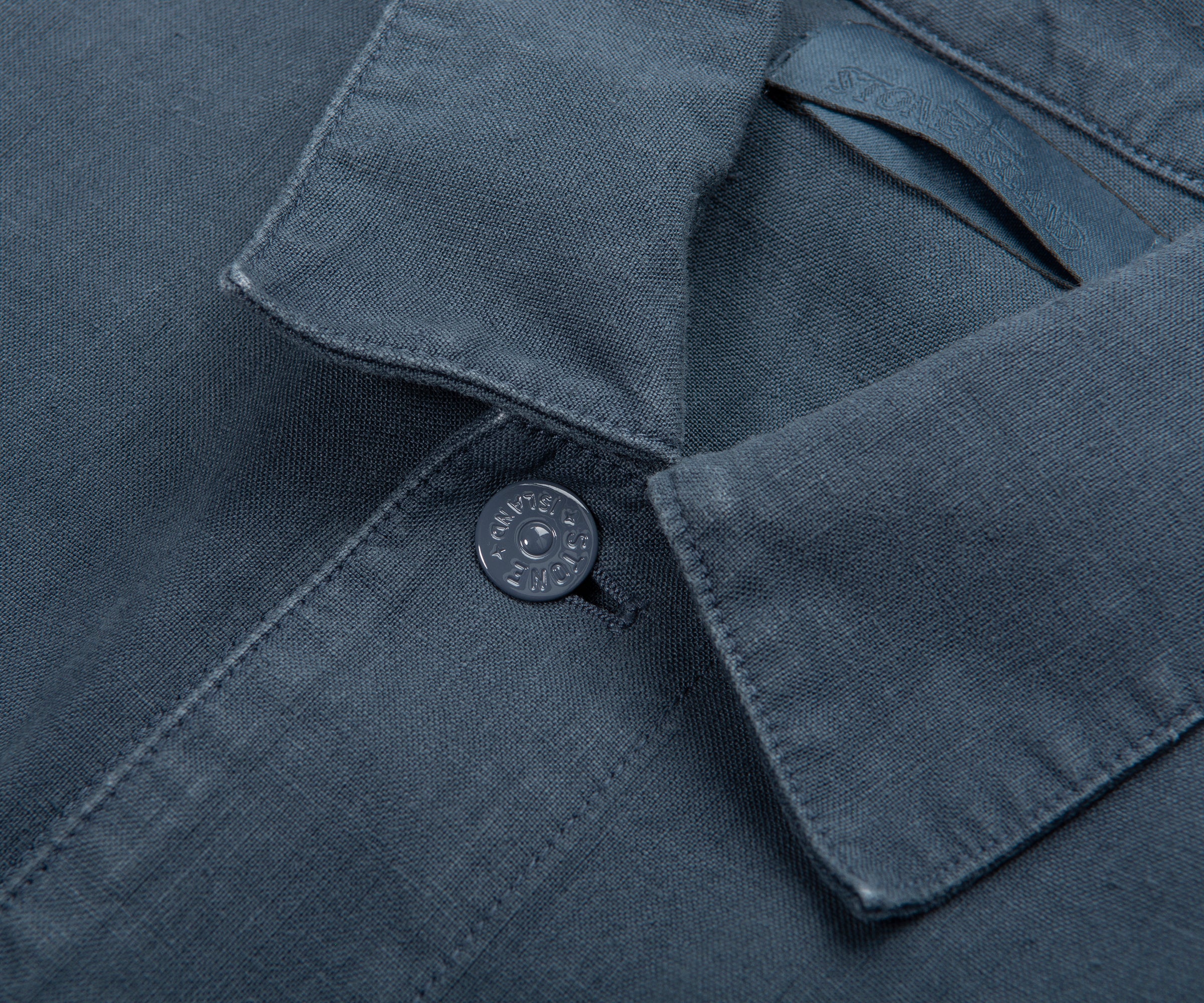 Close-up of a dark blue shirt collar with a button, featuring the brand logo.