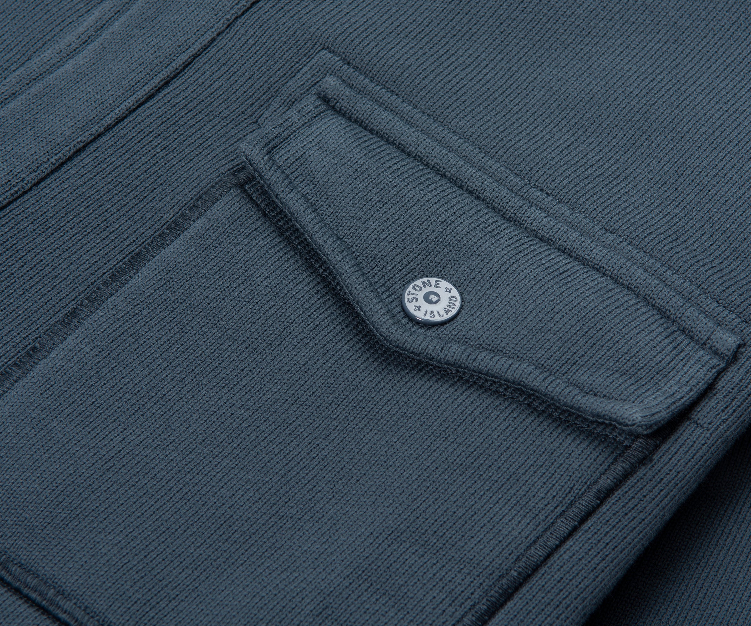 Close-up of a dark gray fabric with a button, likely from a jacket or coat.