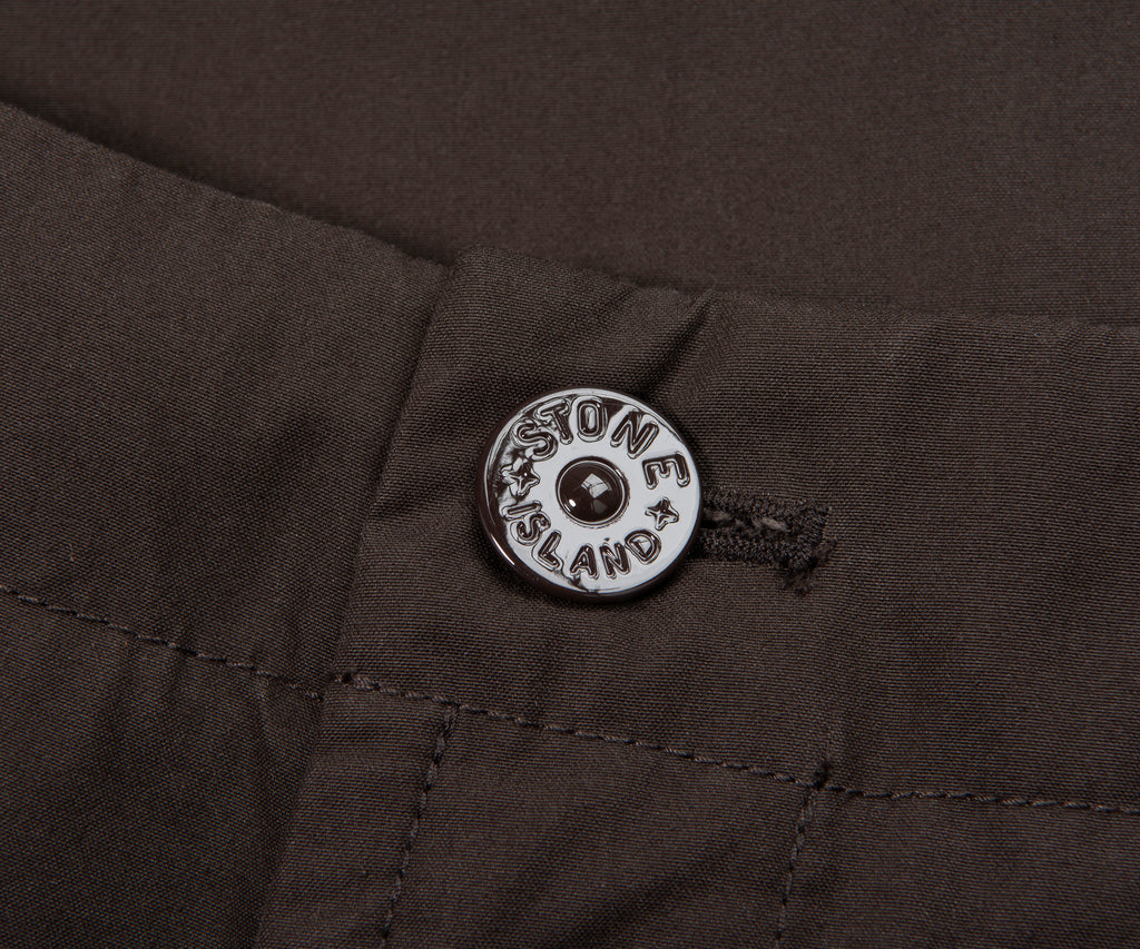 Close-up of a button on a dark fabric with 'Massone Island' branding.