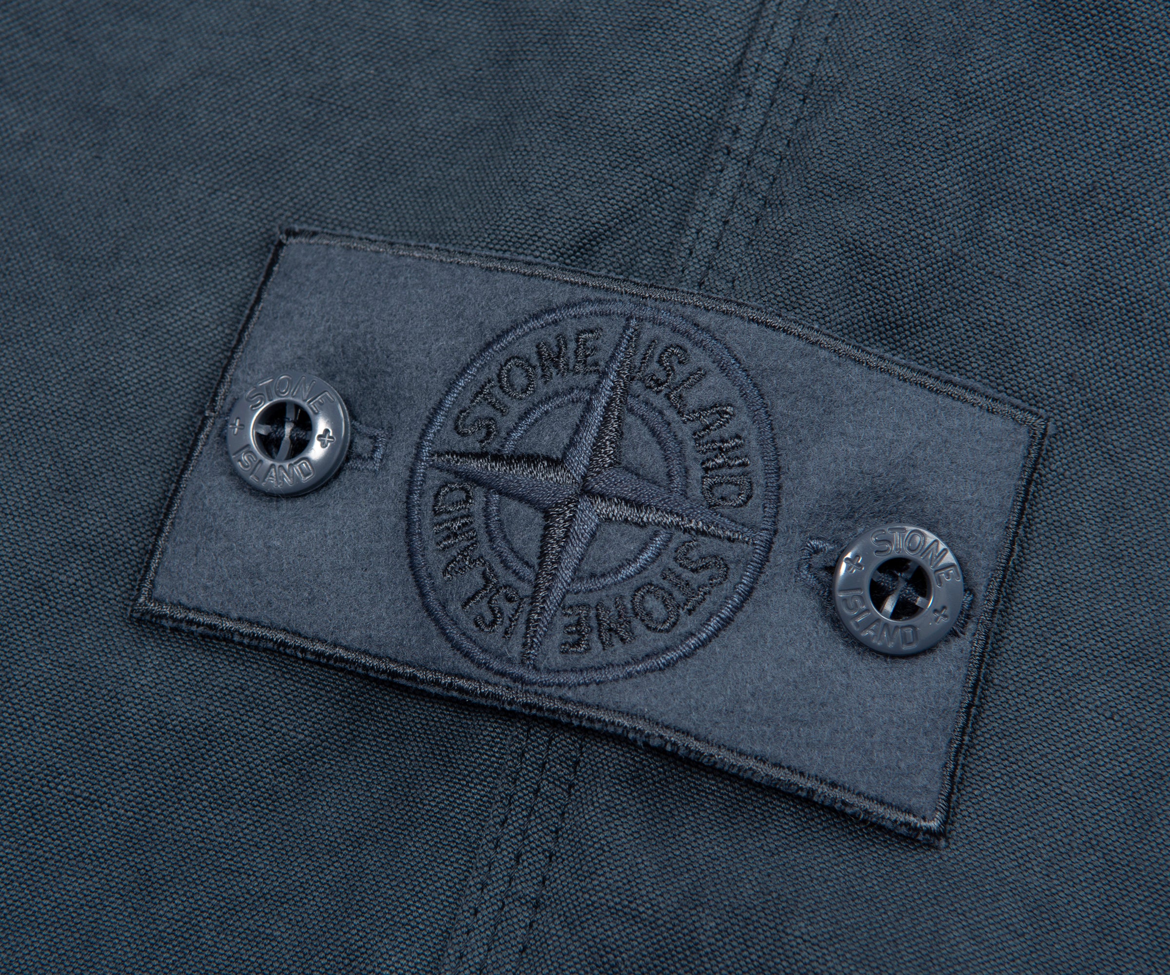 Close-up of a Stone Island label on a dark fabric background