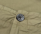 Close-up of a button on a green fabric with 'Stone Island' branding.