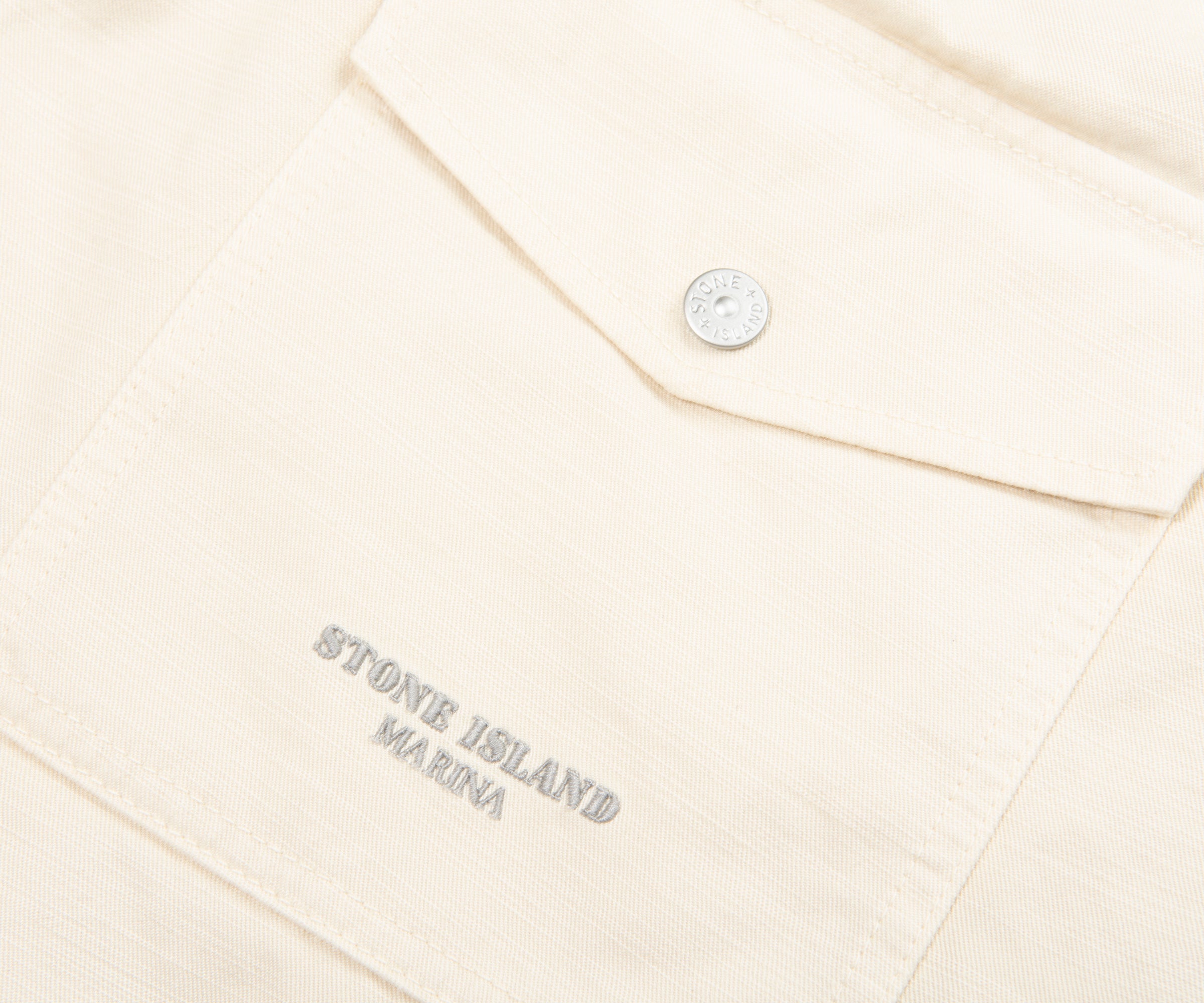 Close-up of a beige garment with 'Stone Island Marina' embroidery on a white background