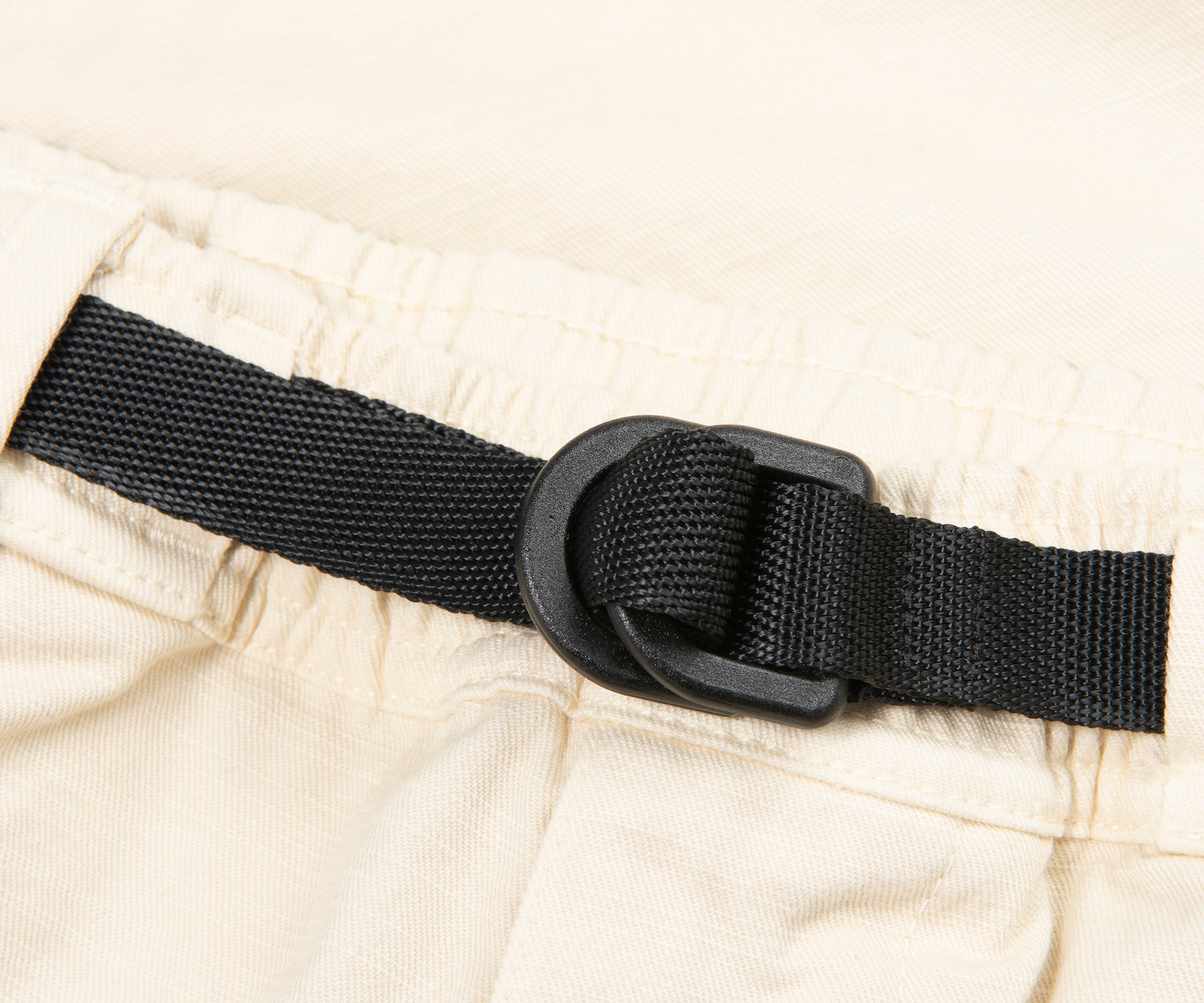 Close-up of a black belt with a buckle on beige pants